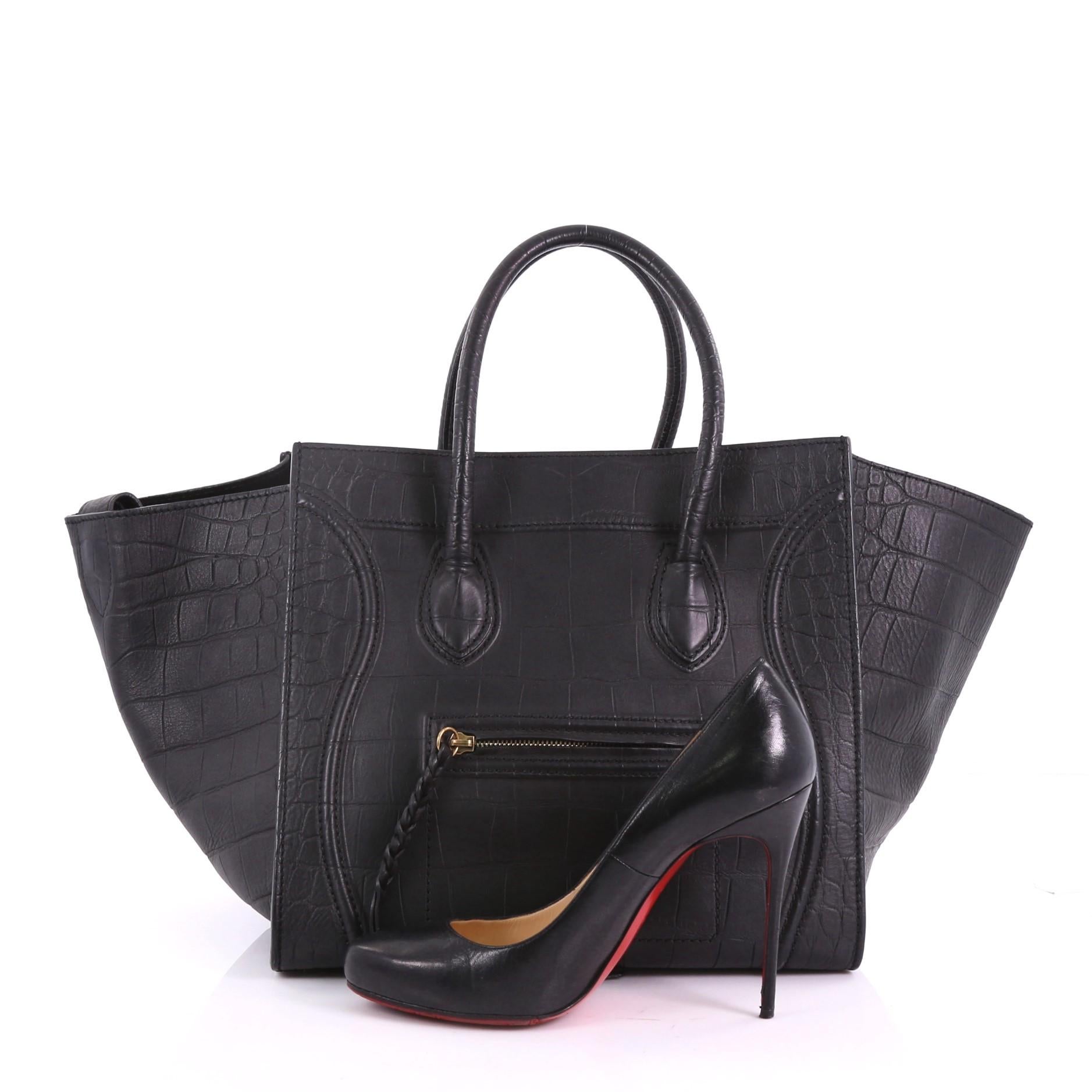 This Celine Phantom Handbag Crocodile Embossed Leather Medium, crafted in black crocodile embossed leather, features dual rolled handles, exterior zip pocket, and gold-tone hardware. It opens to a black suede interior with zip pocket. **Note: Shoe