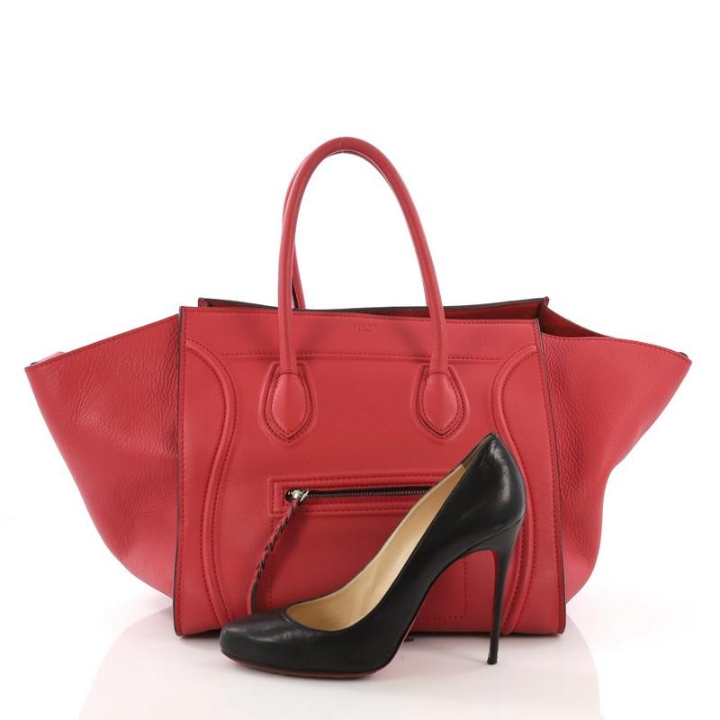 This Celine Phantom Handbag Grainy Leather Medium, crafted in red grainy leather, features dual rolled handles, front zip pocket, and aged silver-tone hardware. It opens to a red suede interior with side zip pocket. **Note: Shoe photographed is used