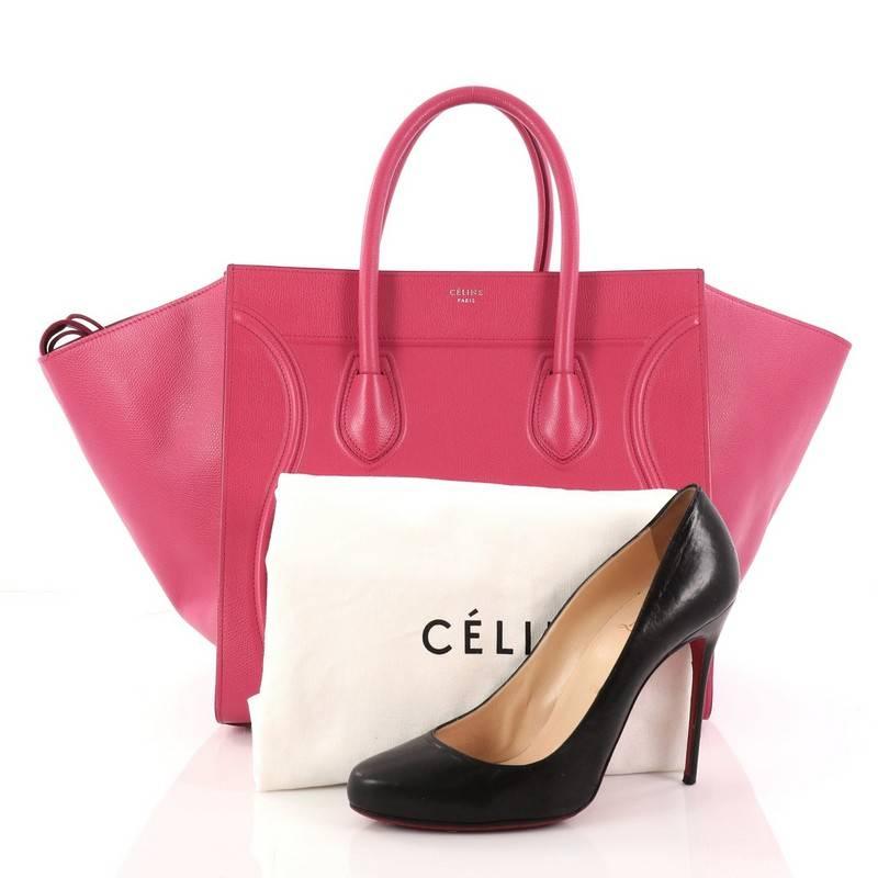 This authentic Celine Phantom Handbag Textured Leather Medium is one of the most sought-after bags beloved by fashionistas. Crafted from pink textured leather, this minimalist tote features dual-rolled handles, an exterior front pocket, protective