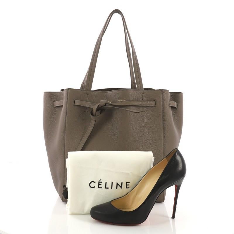 This Celine Phantom Tie Cabas Tote Leather Small, crafted from taupe leather, features dual flat tall handles, stamped Celine logo, and gold-tone hardware. Its drawstring tie closure opens to a taupe suede interior with side zip pocket. **Note: Shoe