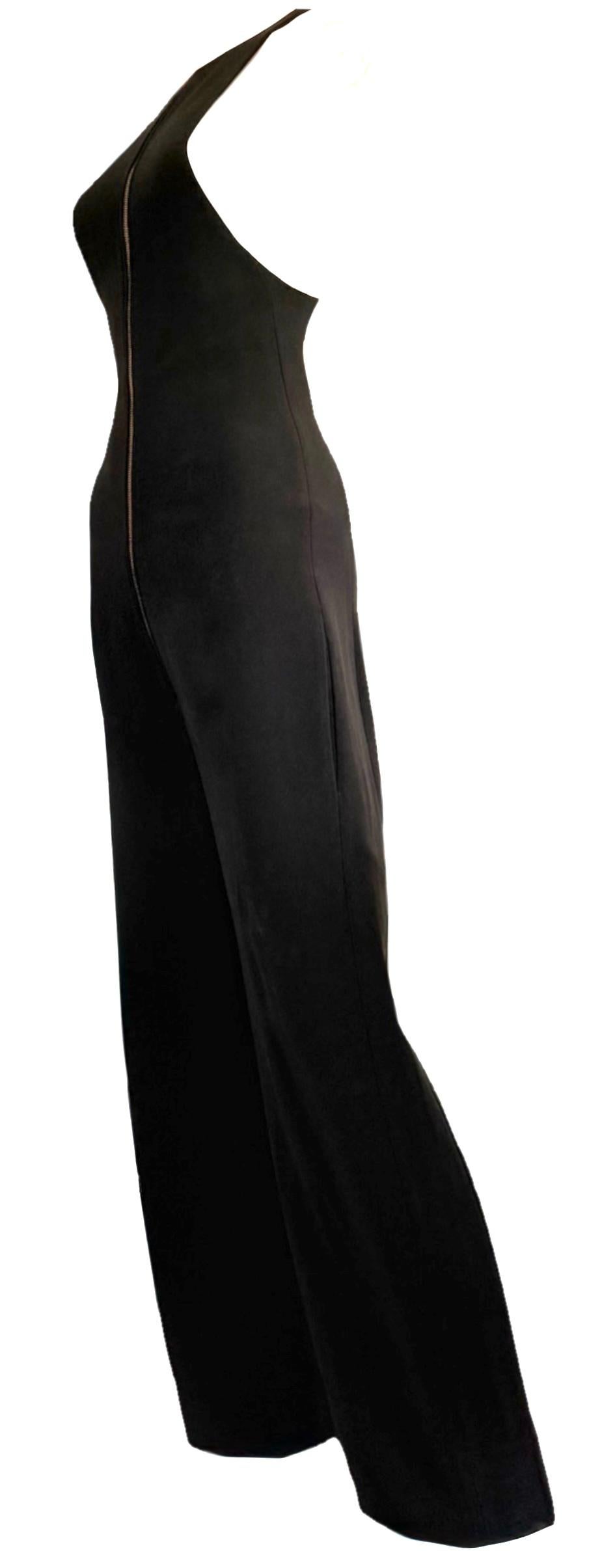 Un design iconico del mandato di Phoebe Philo a Céline, questa tuta in crêpe nero ha debuttato sulla passerella della primavera 2011. La silhouette minimalista presenta una cerniera frontale a vista color oro, una scollatura a farfalla, pantaloni a