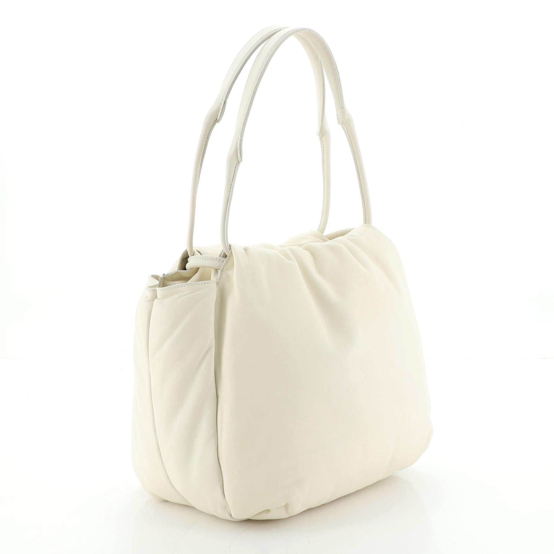 This Celine Pillow Bucket Bag Leather, crafted from neutral leather, features a leather top handle. Its drawstring closure opens to a neutral leather interior with side slip pockets. 

Estimated Retail Price: $2,800
Condition: Very good. Light