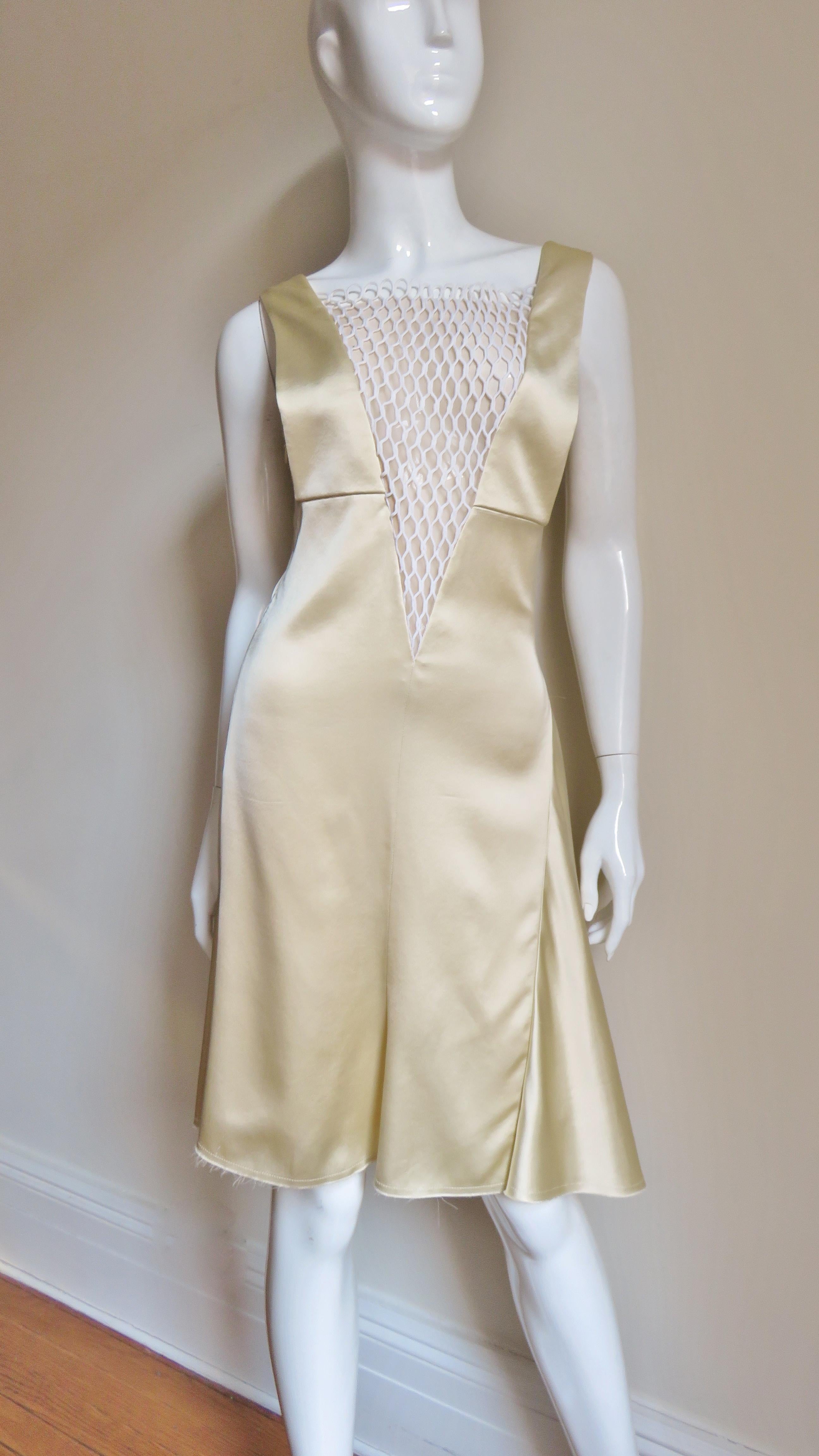 A gorgeous light golden yellow silk dress from Celine.  It has a deep plunging to the waist V neck with nude mesh under white netting. The bodice is fitted, the skirt is fuller with gores at the side and center back.  It is fully lined in matching