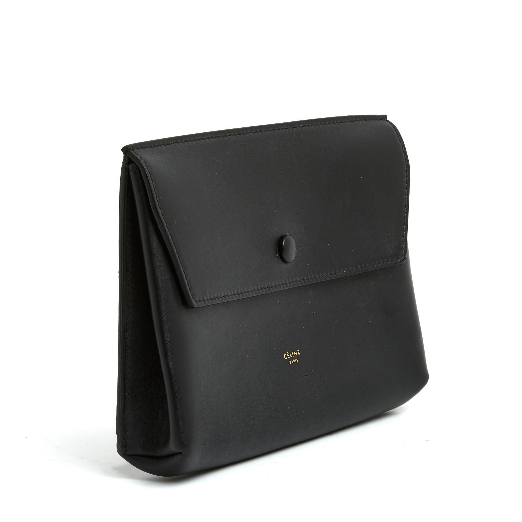 Pochette Céline par Phoebe Philo en cuir noir épais, lisse et mat, intérieur non doublé, fermeture à rabat par un bouton pression recouvert de cuir. Largeur 21 cm x hauteur 14,5 cm x profondeur 4 cm. Le cuir présente quelques marques d'ongles mais
