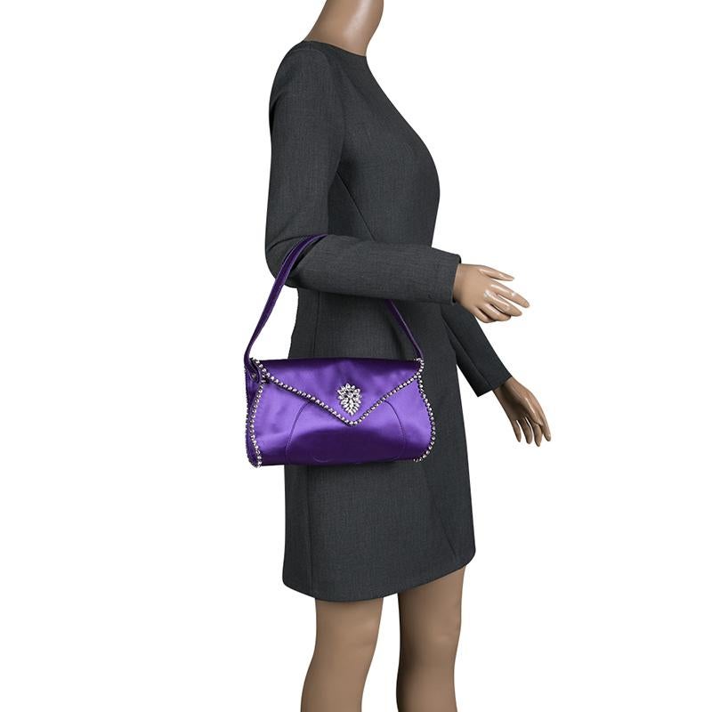 Introduce elegance and color to your evening ensemble with this shoulder bag from Celine. Utterly feminine and styled in a petite yet structured way, the bag is crafted in purple satin and outlined with crystal embellishments. A notable flower motif