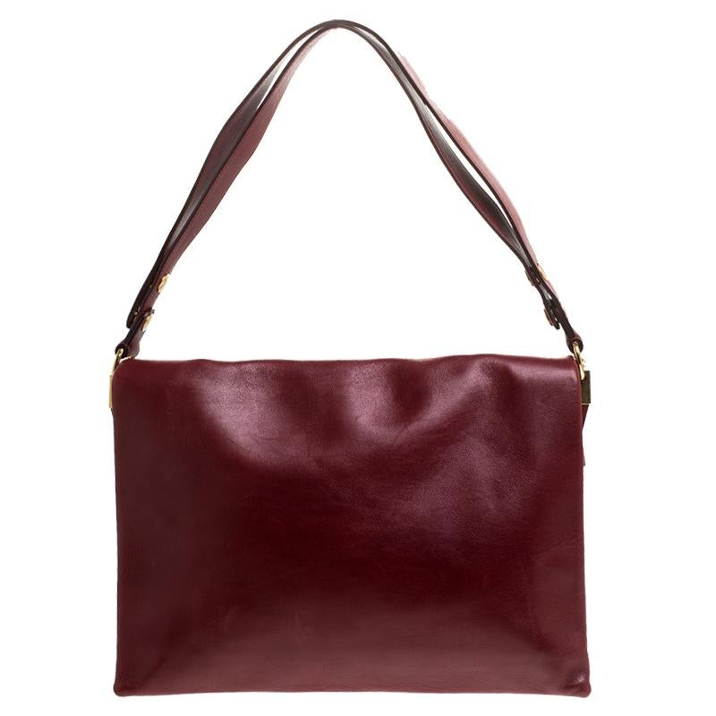 Carry along a mark of sophistication with this simple yet attractive Celine bag. It has been crafted in red calfskin leather. The bag features a top handle and flap closure with blade gold-tone detailing. The interior is leather-lined and has two