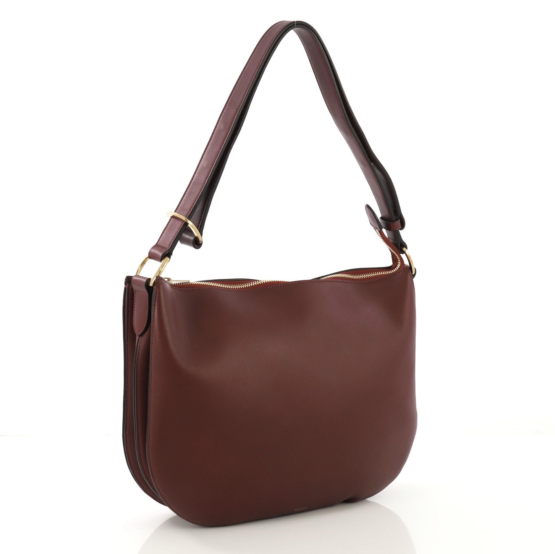 This Celine Saddle Bag Calfskin Medium, crafted in burgundy leather, features adjustable leather crossbody strap with gold-tone links, buckle and gold-tone hardware. Its zip closure opens to a purple suede interior **Note: 

Estimated Retail Price:
