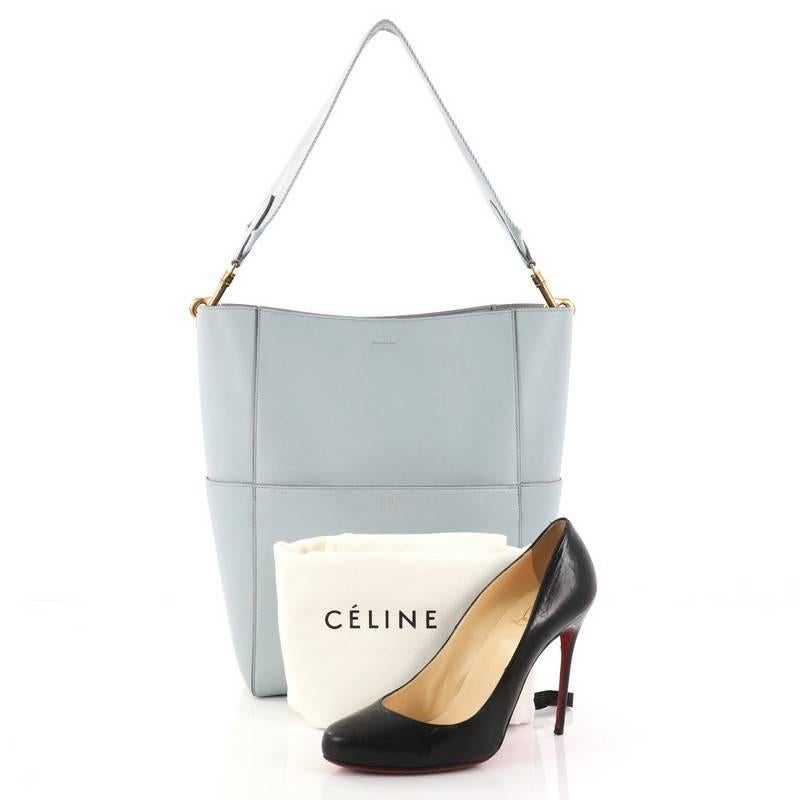 This authentic Celine Sangle Seau Handbag Calfskin Large balances a simple yet luxurious style perfect for an on-the-go woman. Crafted from light blue calfskin leather, this minimalist bucket bag features a detachable canvas shoulder strap, multiple