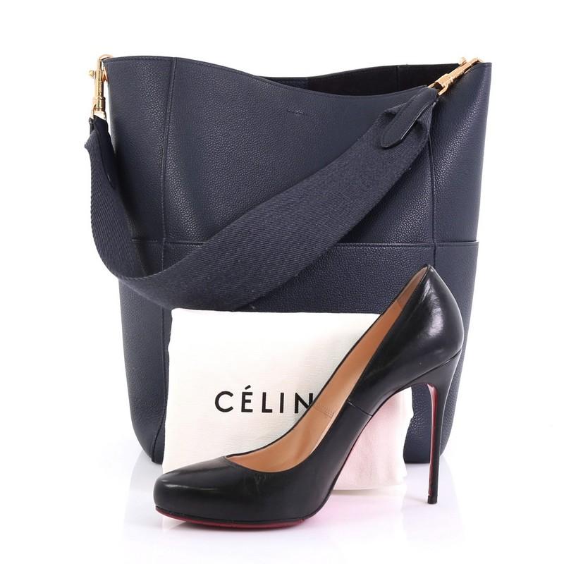 This Celine Sangle Seau Handbag Goatskin Large, crafted in navy goatskin leather, features single textile strap, exterior slip pockets, and gold-tone hardware. Its hook closure opens to a navy suede interior with slip pocket. **Note: Shoe