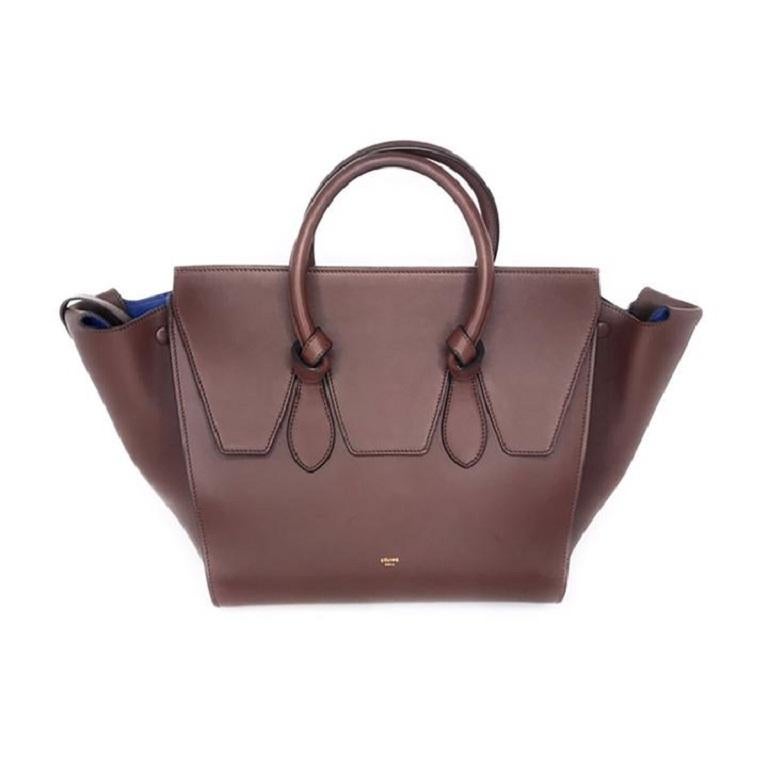 This chic tote offers a different take on the iconic luggage handbag style in the smaller model. Crafted of luxuriously smooth calfskin leather in chocolate brown, this bag features a structured and spacious silhouette with knotted top handles that