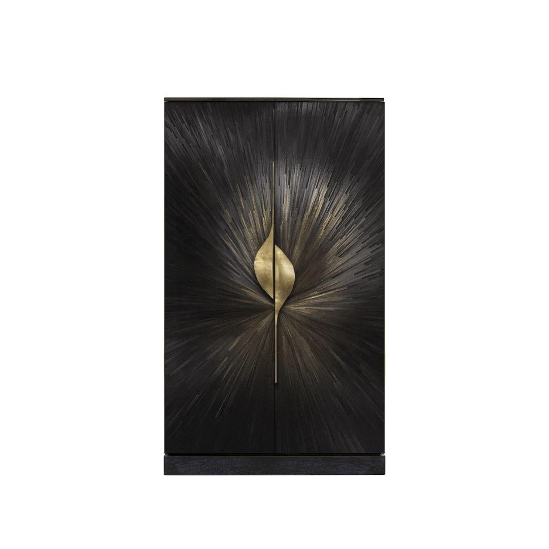 The Celine Straw Armoire is a testament to exceptional craftsmanship, with radiant straw marquetry forming a mesmerizing sunburst effect across its doors. Sculptural cast brass pulls add a touch of allure, while the matte black tulipwood interior