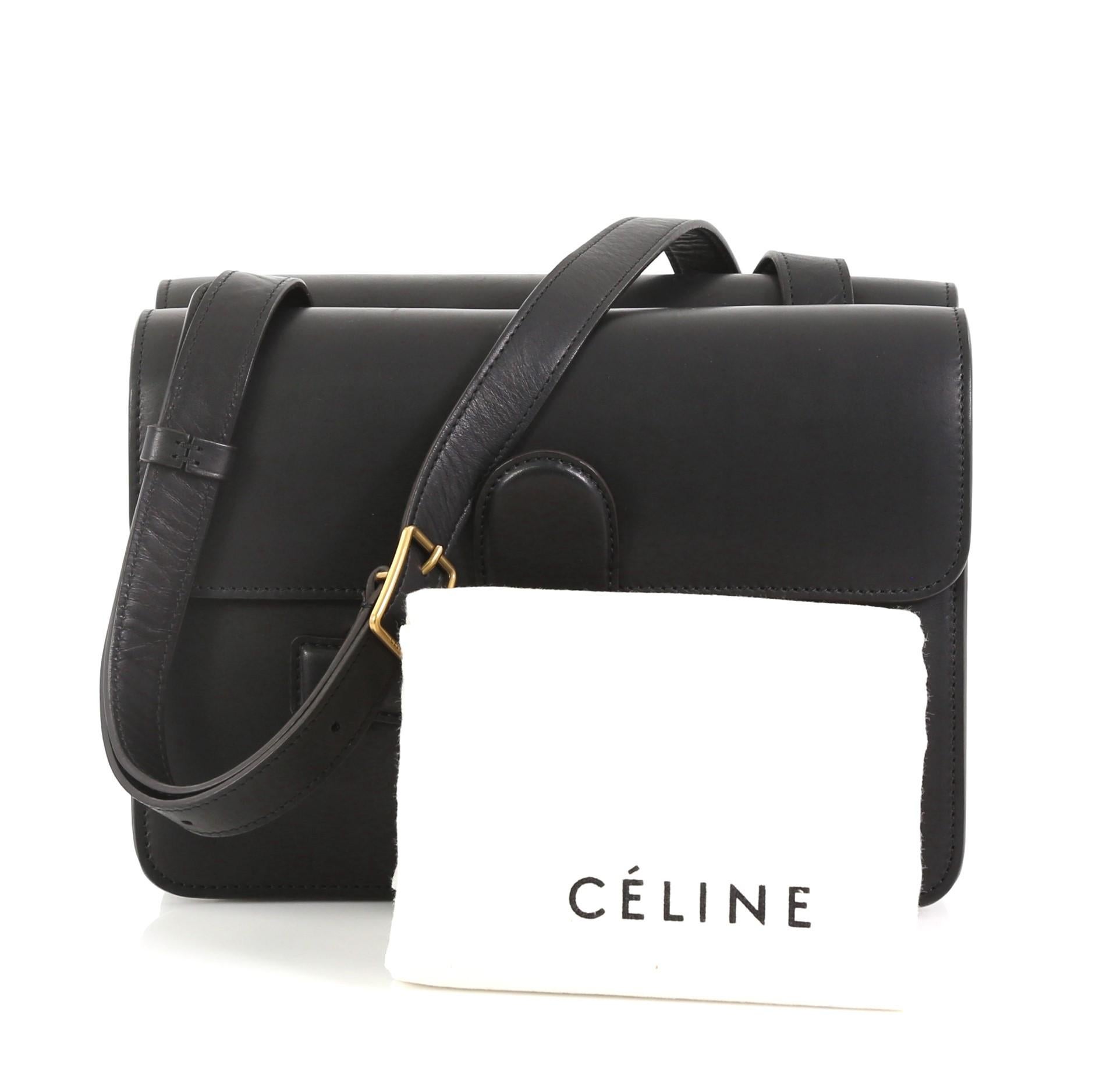 This Celine Symmetrical Shoulder Bag Leather, crafted from black leather, features flat leather should strap, tab insert flap closure at front and back, gusseted sides and gold-tone hardware. Its tab insert opens to a black suede interior with dual