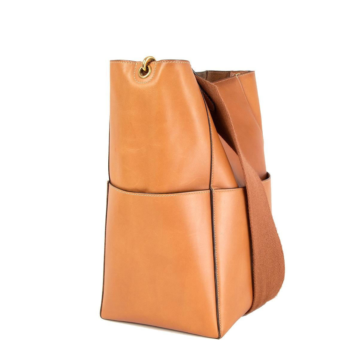 Céline 'Sangle Bucket' shoulder bag in tan natural calfskin featuring gold-tone hardware with four flat outside pockets. Opens with a inner hook closure and is unlined with a flat and zipped pocket against the back. Removable wool shoulder strap.