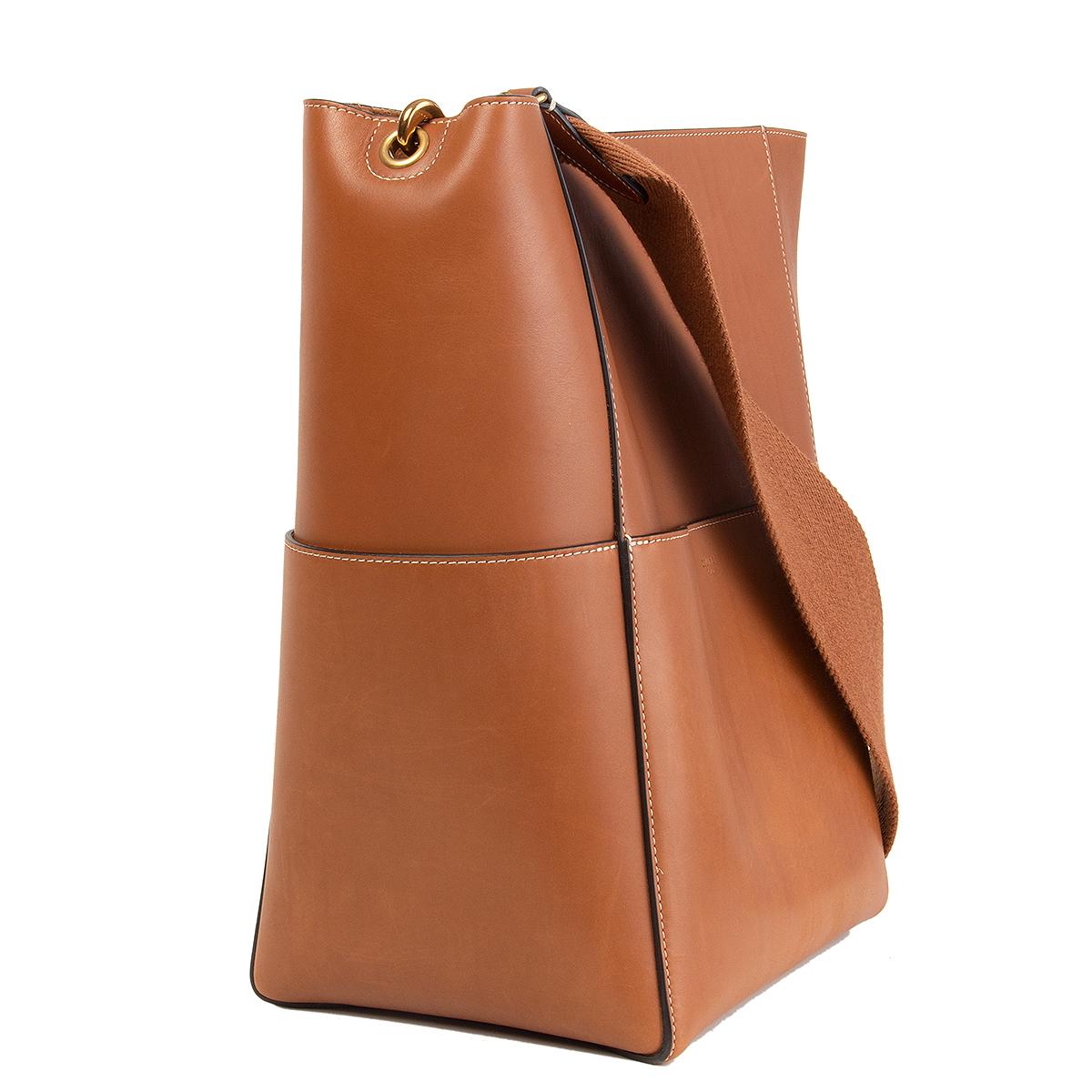 100% authentic Céline 'Sangle Bucket' shoulder bag in tan natural calfskin featuring antique gold-tone hardware with four flat outside pockets. Opens with a inner hook closure and is unlined with a flat and zipped pocket against the back. Removable