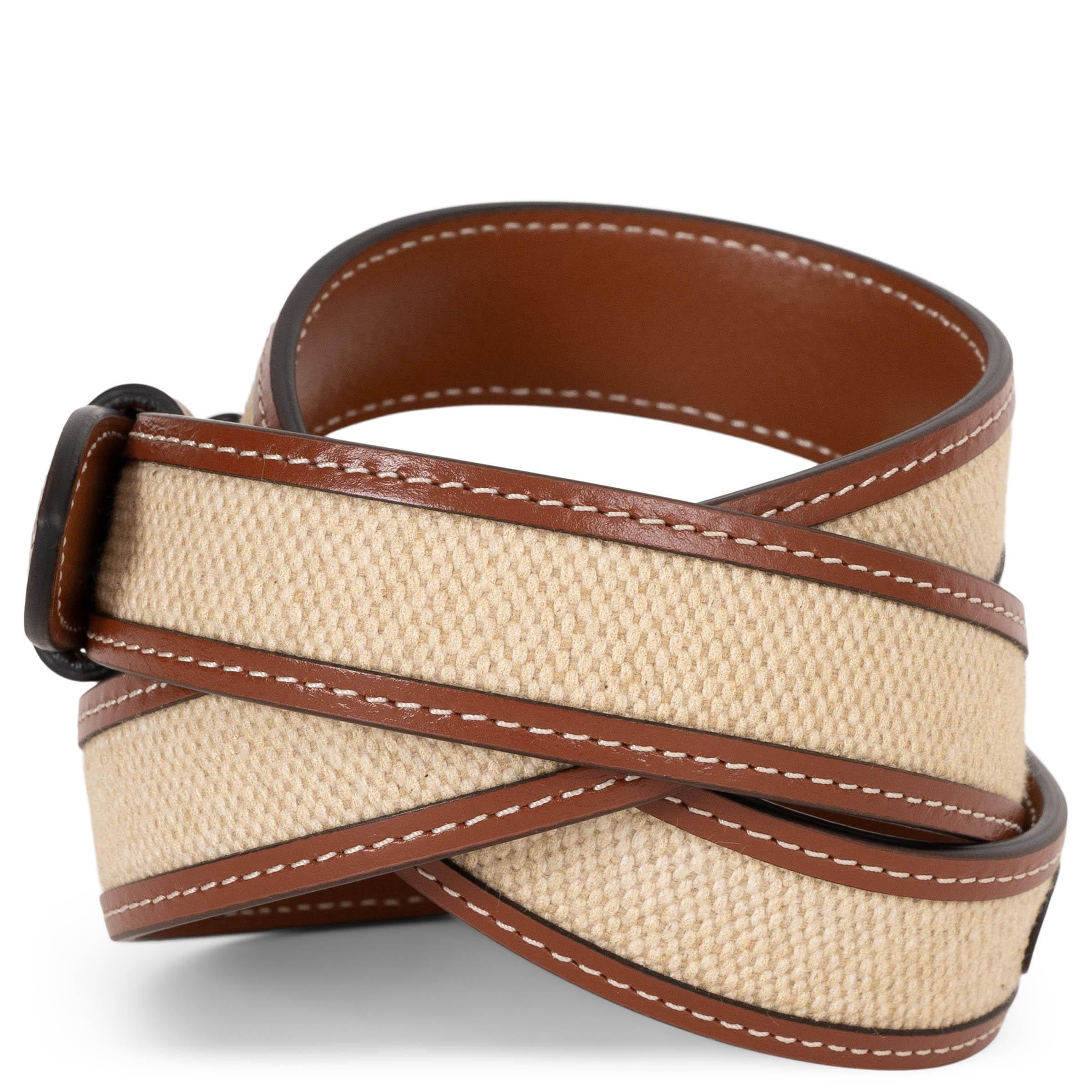 This 100% authentic Celine Medium Triomphe 25mm belt in natural canvas and tan calfskin leather blends classic charm with modern refinement. Featuring a gold-tone Triomphe buckle, it adds a polished touch to any outfit, making it a timeless and