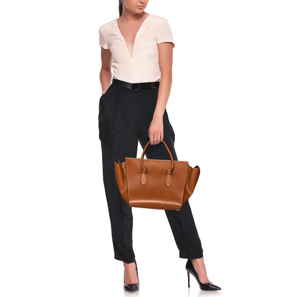 This Tie tote from Celine brings a wonderful mix of fashion and function. Expertly crafted from leather, it comes in a lovely shade of tan with dual top handles and metal studs to protect the base. Made in Italy, it has a spacious interior lined