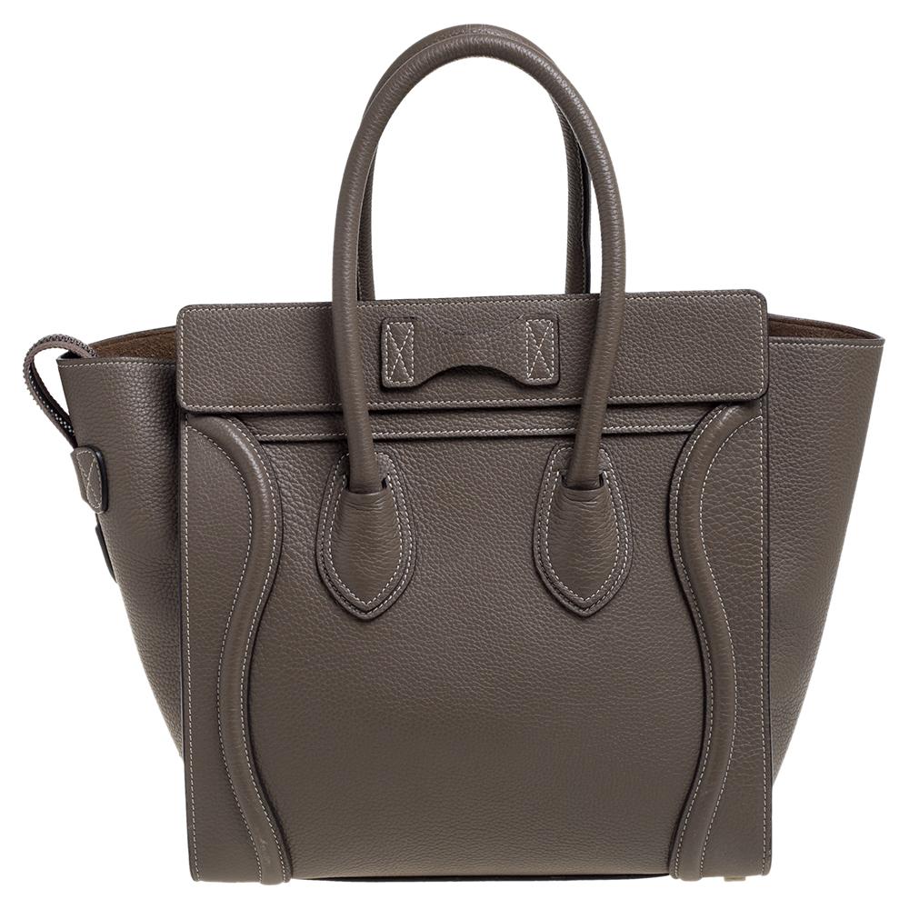 This Celine Luggage tote is stylish, perfect for everyday use, and loved by celebs worldwide. Crafted from leather in a Taupe shade, it features the signature flappy wings, double rolled handles, and a front zip pocket. The top zip closure opens to