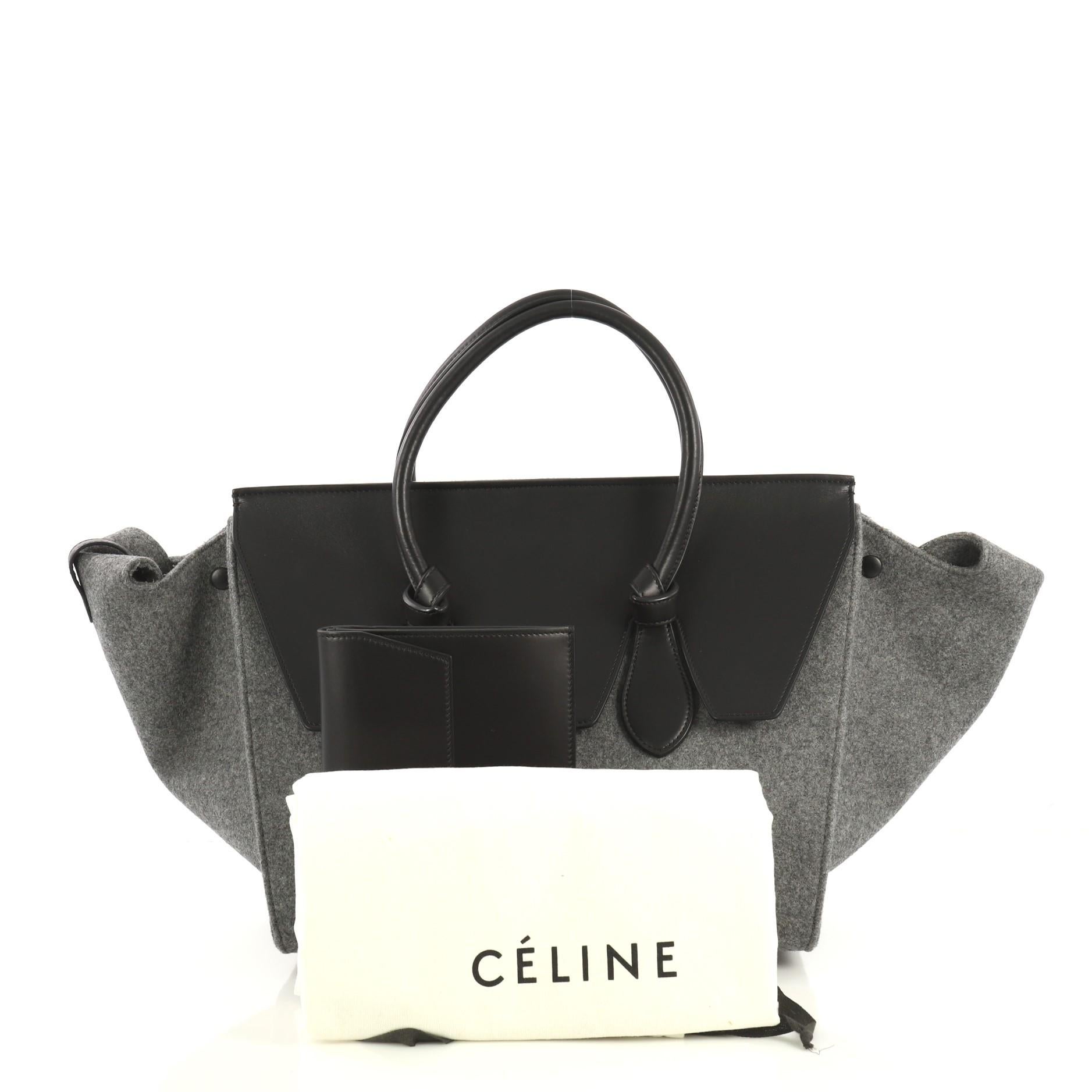 This Celine Tie Knot Tote Leather and Felt Medium, crafted from gray leather and felt, features dual rolled leather handles with knot accents, expandable wings and a top leather flap that can be tucked inside, protective base studs, and gold-tone