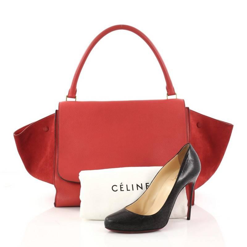 This authentic Celine Trapeze Handbag Leather Large is a modern minimalist design with a playful twist in subdued colors. Crafted from red leather and suede wings, this classic bag features a top rolled handle, side snap closures, exterior back zip