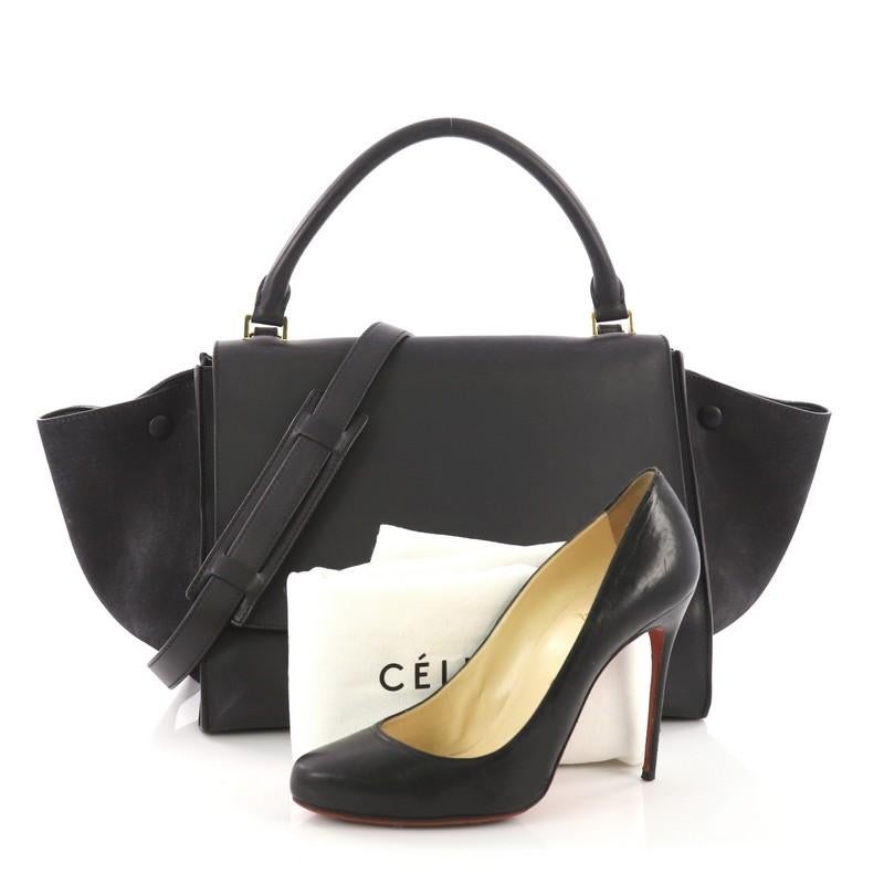 This Celine Trapeze Handbag Leather Medium, crafted from navy leather and suede, features a rolled top handle, exterior back zipped pocket, and gold-tone hardware accents. Its square flip-lock closure opens to a navy leather interior with slip