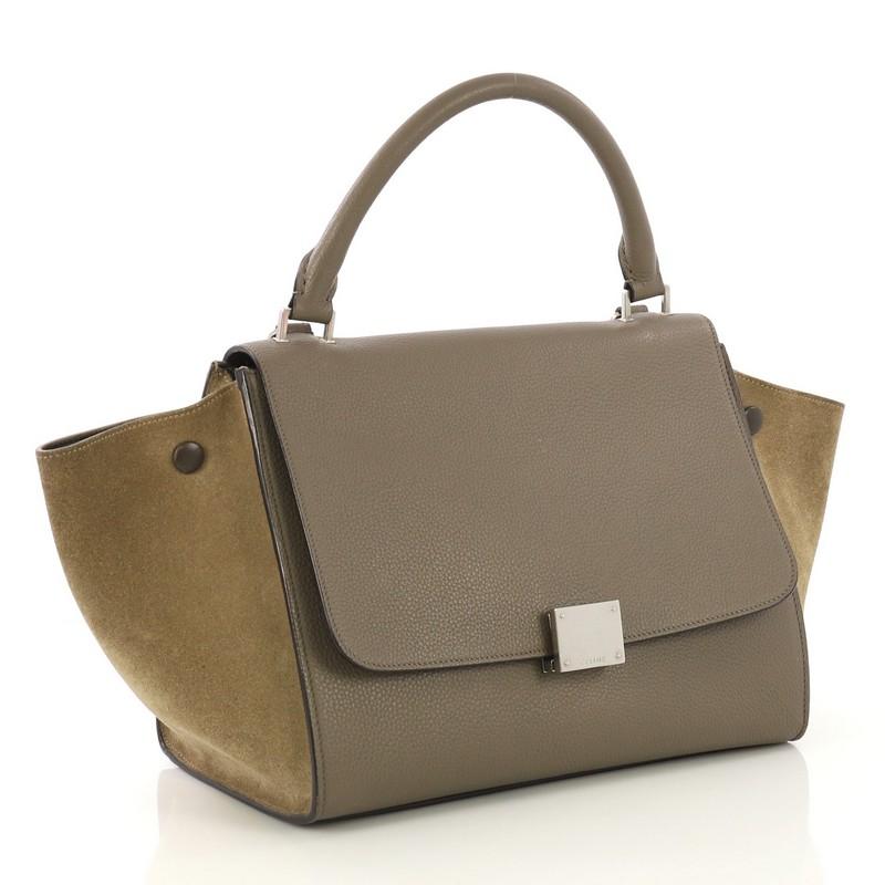 This Celine Trapeze Handbag Leather Small, crafted from taupe leather and beige suede, features a rolled top handle, exterior back zip pocket, and silver-tone hardware. Its square flip-lock closure opens to a dark taupe leather interior with slip