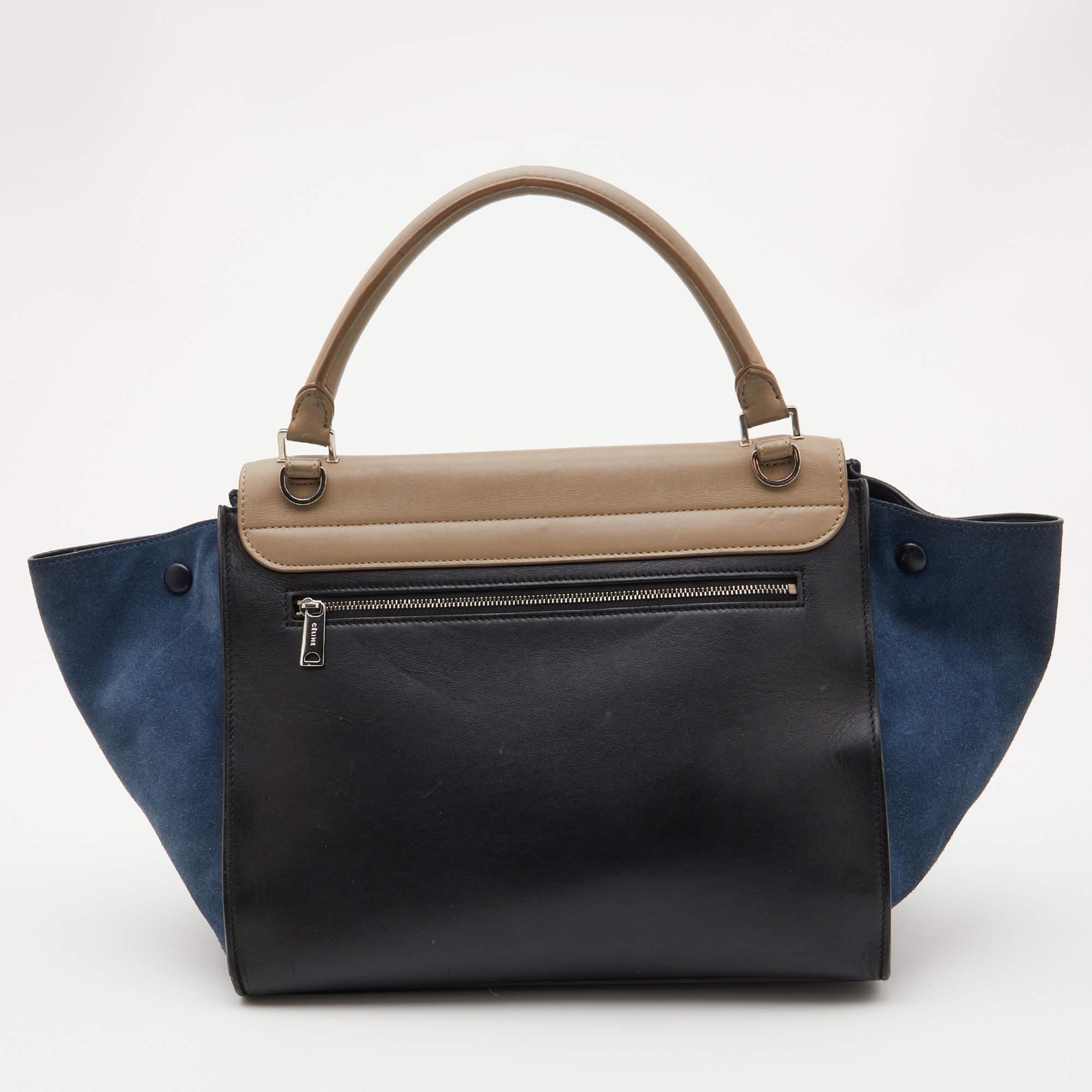 Featuring a simple yet luxurious style, this Celine bag is a thoughtful purchase with its classy aesthetics. Crafted from leather and suede, it is characterized by flappy wings, silver-tone hardware, and a back zipper pocket. The front flap of this