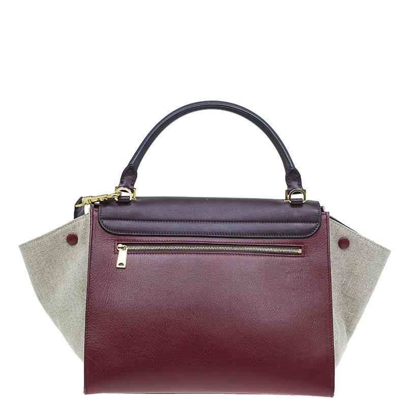 This Celine tri-color bag comes crafted in maroon and brown leather and beige canvas. This trapeze bag features sturdy top handle and is embellished with gold-tone hardware. It has a detachable shoulder strap and displays a front flap and a top