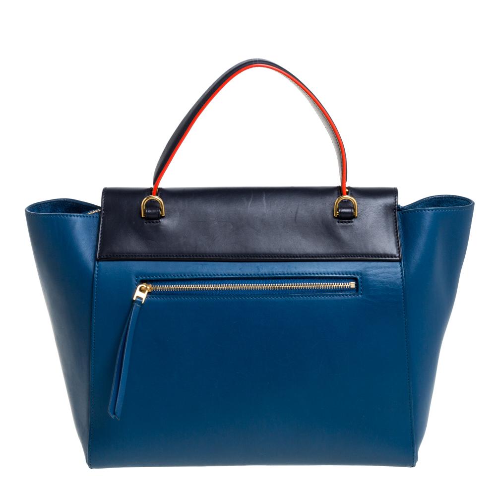 Bags from Celine are symbols of excellent craftsmanship and timeless design. This tricolor creation has been crafted from leather and styled with a front flap and belt details. It flaunts a single top handle, a zip pocket at the back, and a spacious