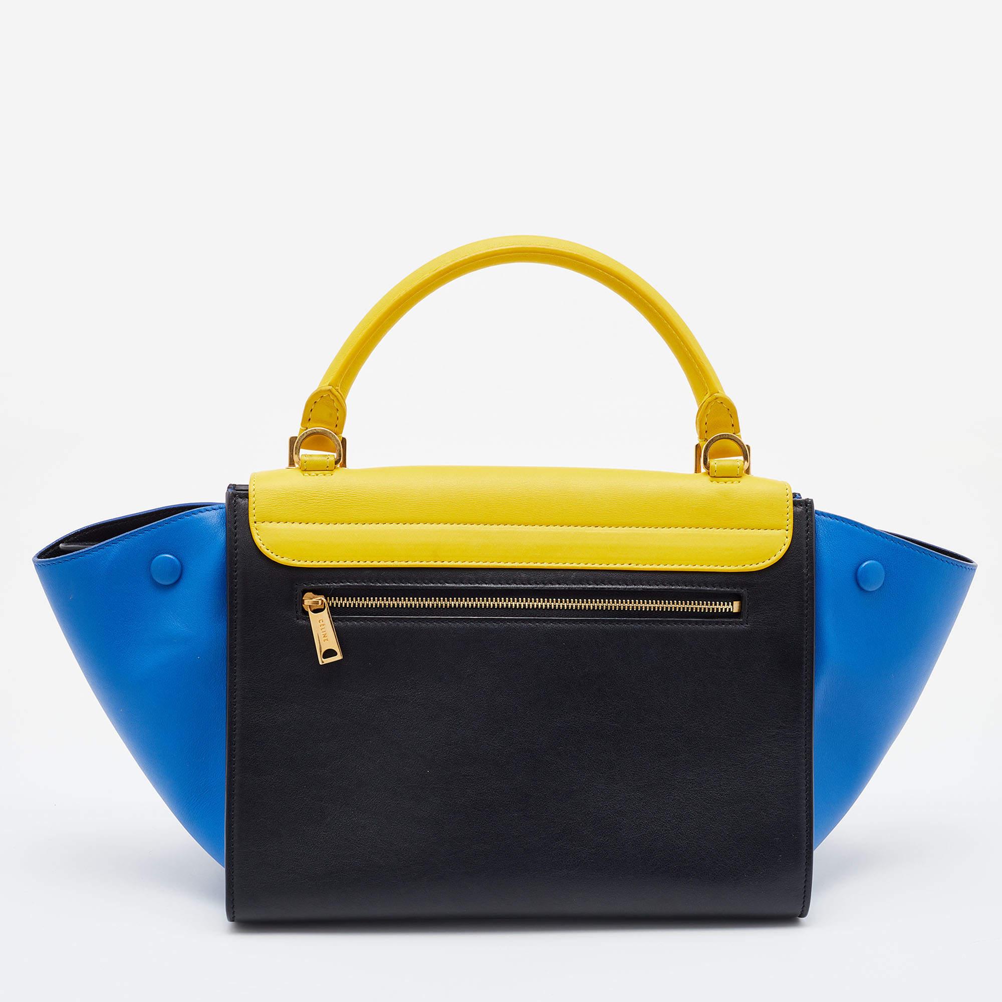 Featuring a simple yet luxurious style, this Celine bag is a thoughtful purchase with its classy aesthetics. Crafted from tri-color leather, it is characterized by flappy wings, gold-tone hardware, and a back zipper pocket. The front flap of this