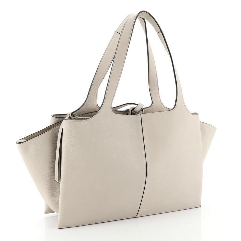 This Celine Tri-Fold Shoulder Bag Grained Calfskin Medium, crafted from neutral grained calfskin leather, features dual flat leather handles, expandable side wings, and silver-tone hardware. It opens to a neutral suede interior with two open