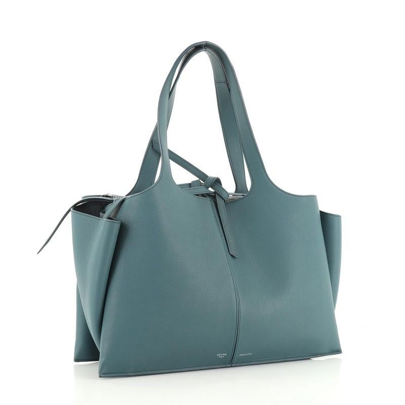 This Celine Tri-Fold Shoulder Bag Grained Calfskin Medium, crafted from green grained calfskin leather, features dual flat leather handles, expandable side wings, and silver-tone hardware. It opens to a green suede interior with two open