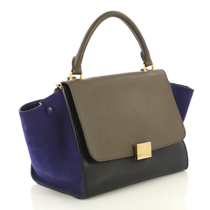 This Celine Tricolor Trapeze Handbag Leather Medium, crafted from black and neutral leather and blue suede, features a rolled leather handle, exterior back zip pocket, and aged gold-tone hardware. Its square flip-lock and zip closures open to a