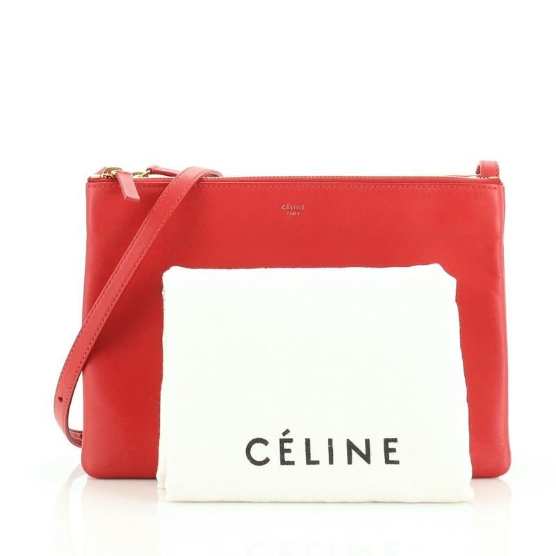 This Celine Trio Crossbody Bag Leather Large, crafted from red leather, features an adjustable shoulder strap and gold-tone hardware. Its triple zip closure opens to a gray jersey interior. 

Estimated Retail Price: $1,300
Condition: Excellent.