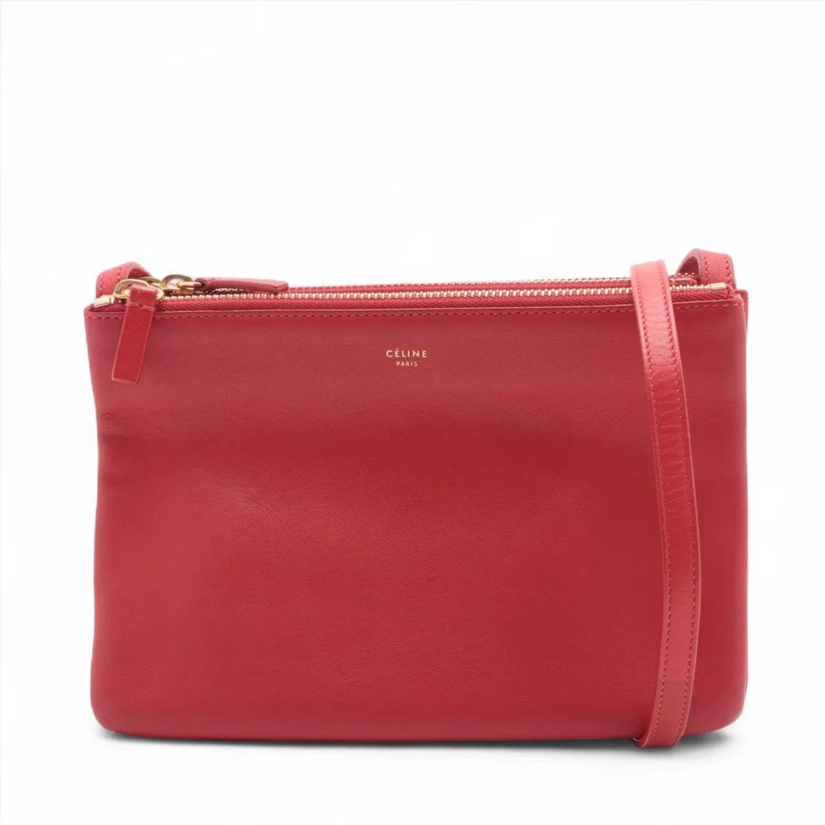 Le sac à bandoulière en cuir Trio de Celine en rouge est un classique minimaliste qui allie une élégance discrète à un design pratique. Confectionné en cuir lisse et souple dans une teinte rouge audacieuse, ce sac à bandoulière polyvalent est doté