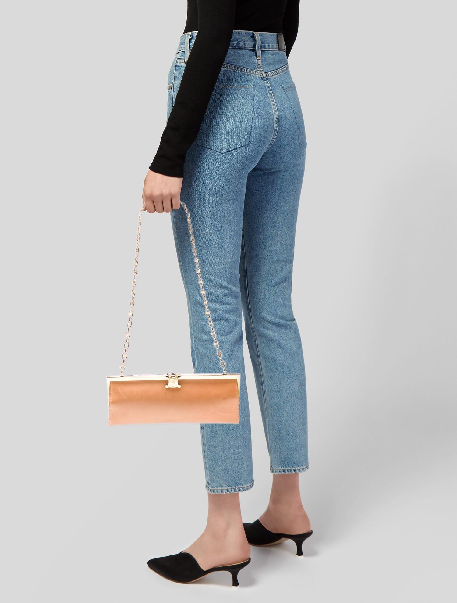 This Celine Triomphe Gold Framed Bag is constructed of neutral leather with gold-tone hardware and chain-link accents. The bag features a chain-link shoulder strap and a structured frame design. The bag is secured with Celine’s signature Triomphe