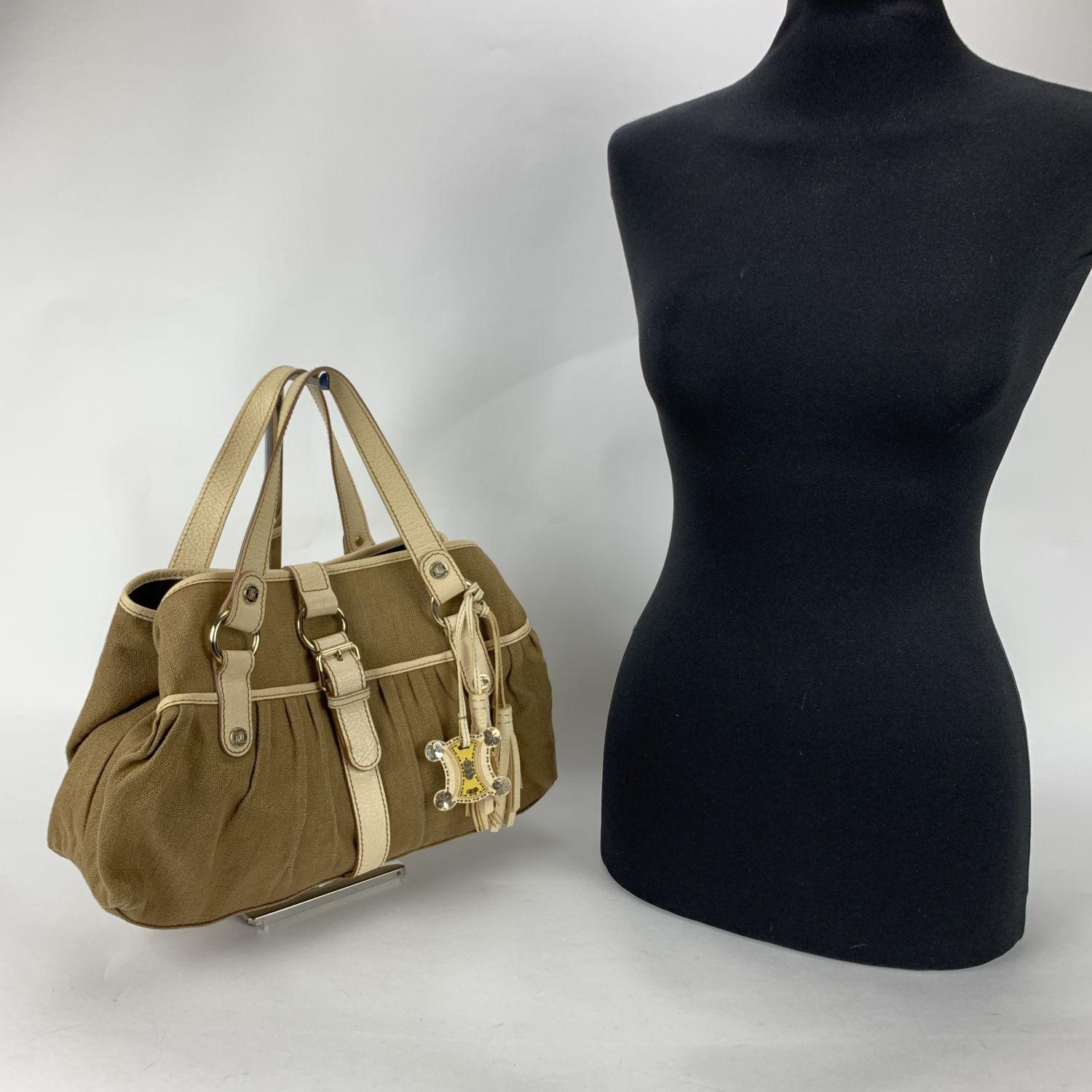 Celine Brown Canvas Duffel tote bag with beige genuine leather handles and trim. Pleats detailing on the front. Fold-over strap with magnetic button closure. Tassels and Macadam pendants.Canvas lining. 1 side zip pocket and 1 side open pocket