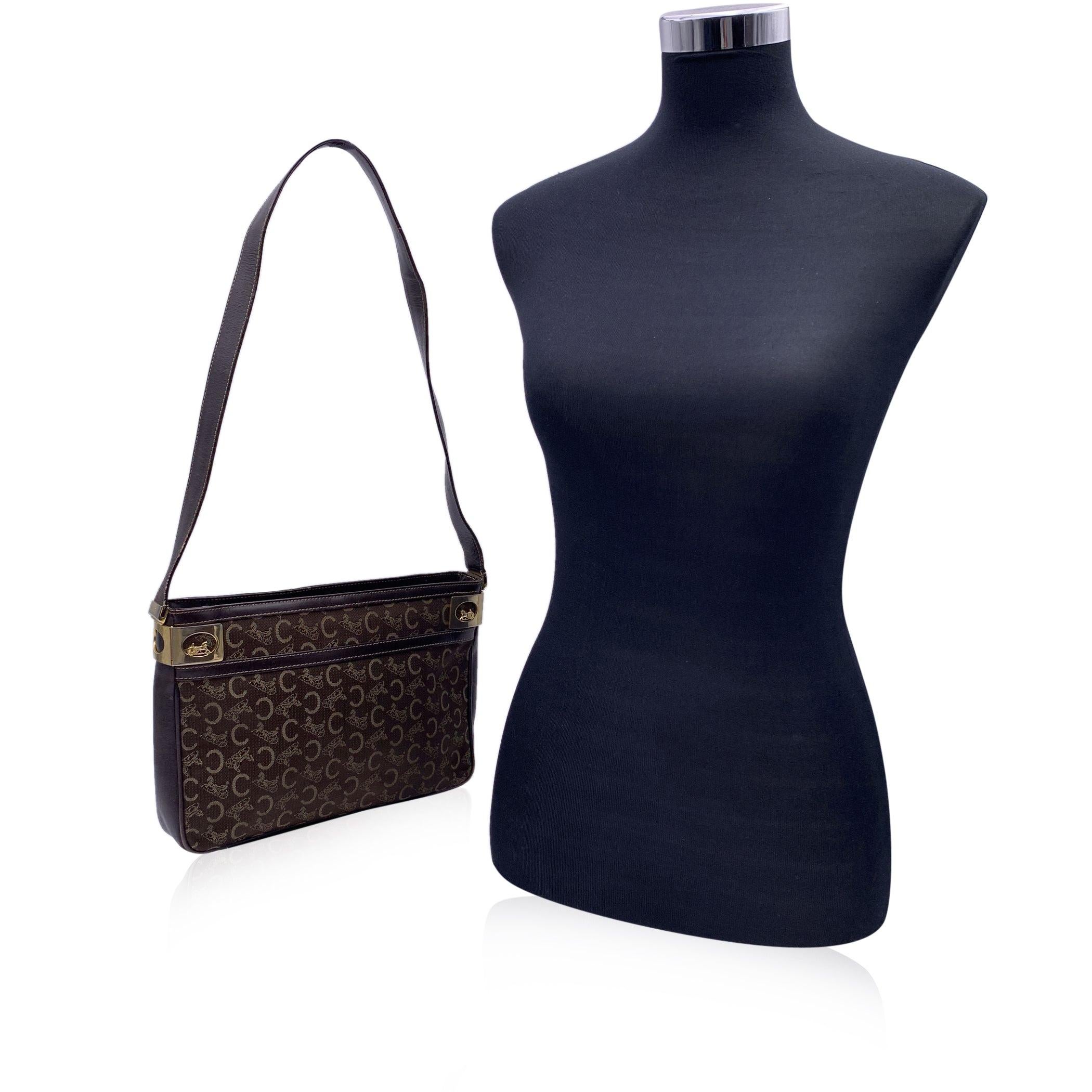 Sac à bandoulière 'C.I.C' de Celine en toile A.I.C. avec garniture et bandoulière en cuir marron. Ferrures Caleche en métal doré sur les côtés. Fermeture à glissière supérieure. Doublure en cuir marron. 1 poche latérale zippée et 1 poche latérale à