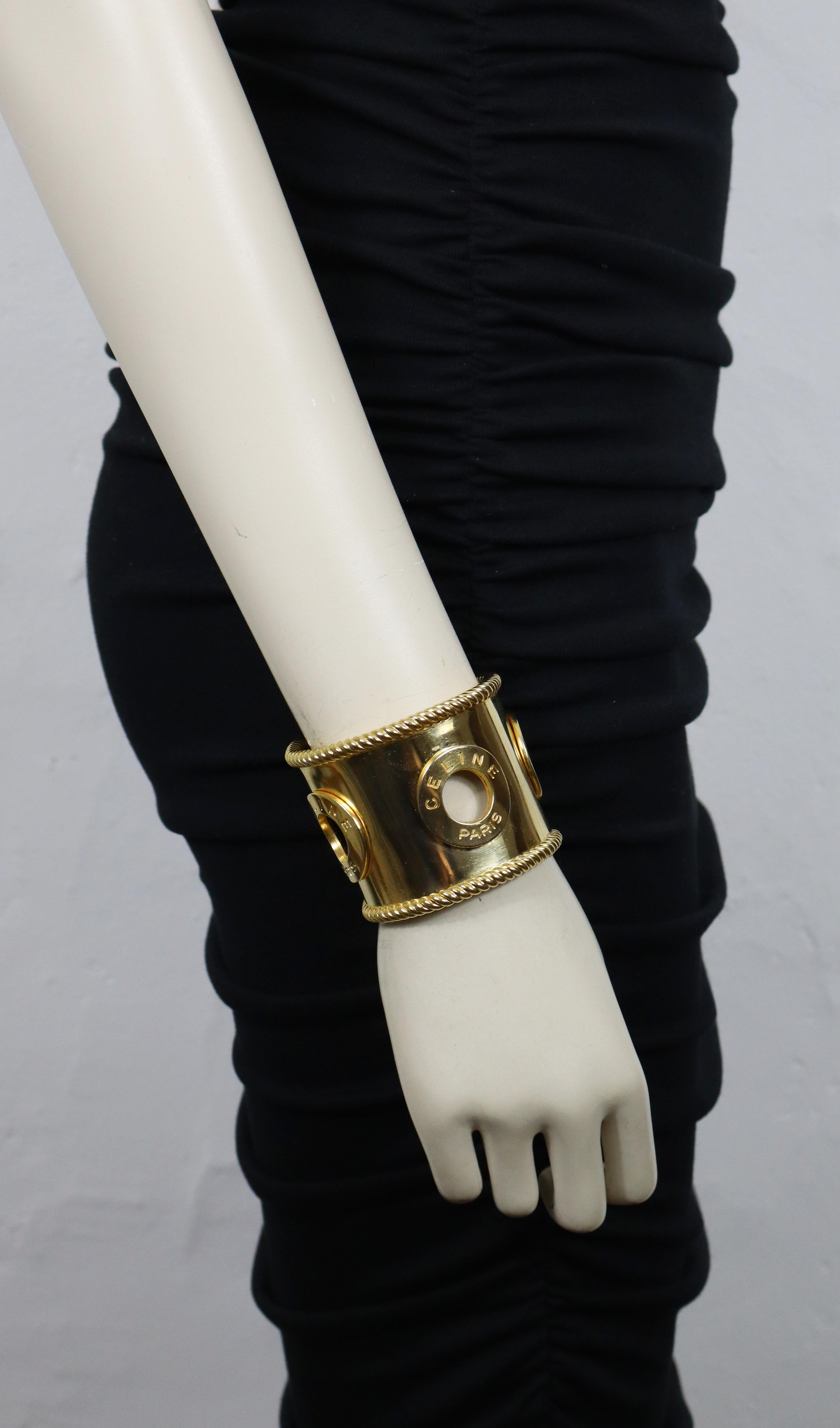 Bracciale vintage CELINE in tonalità oro, con tre anelli traforati con la scritta CELINE PARIS.

Un pezzo che incarna una raffinatezza senza tempo, come mostrato in una pubblicità di Celine (vedi foto).

CELINE 90 Made in Italy.

Misure indicative: