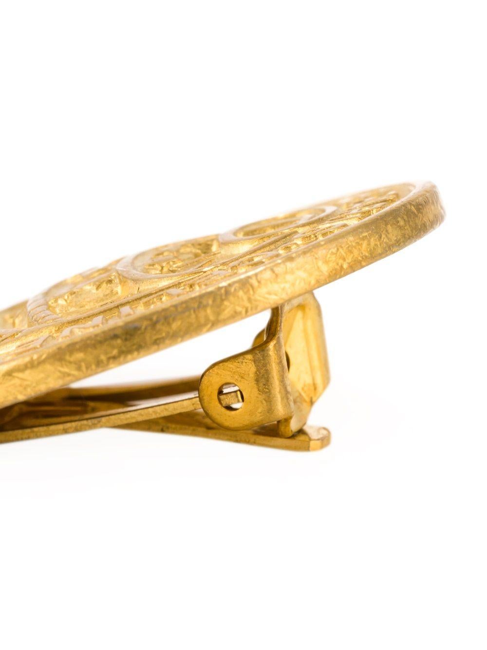 Vintage-Ohrringe mit goldfarbenem Medaillon und Clipverschluss von Céline. 

Farbe: Gold, Perle

Material: Vergoldetes Metall

Abmessungen: Breite: 2,5cm

Zustand: Sehr guter Zustand. 




