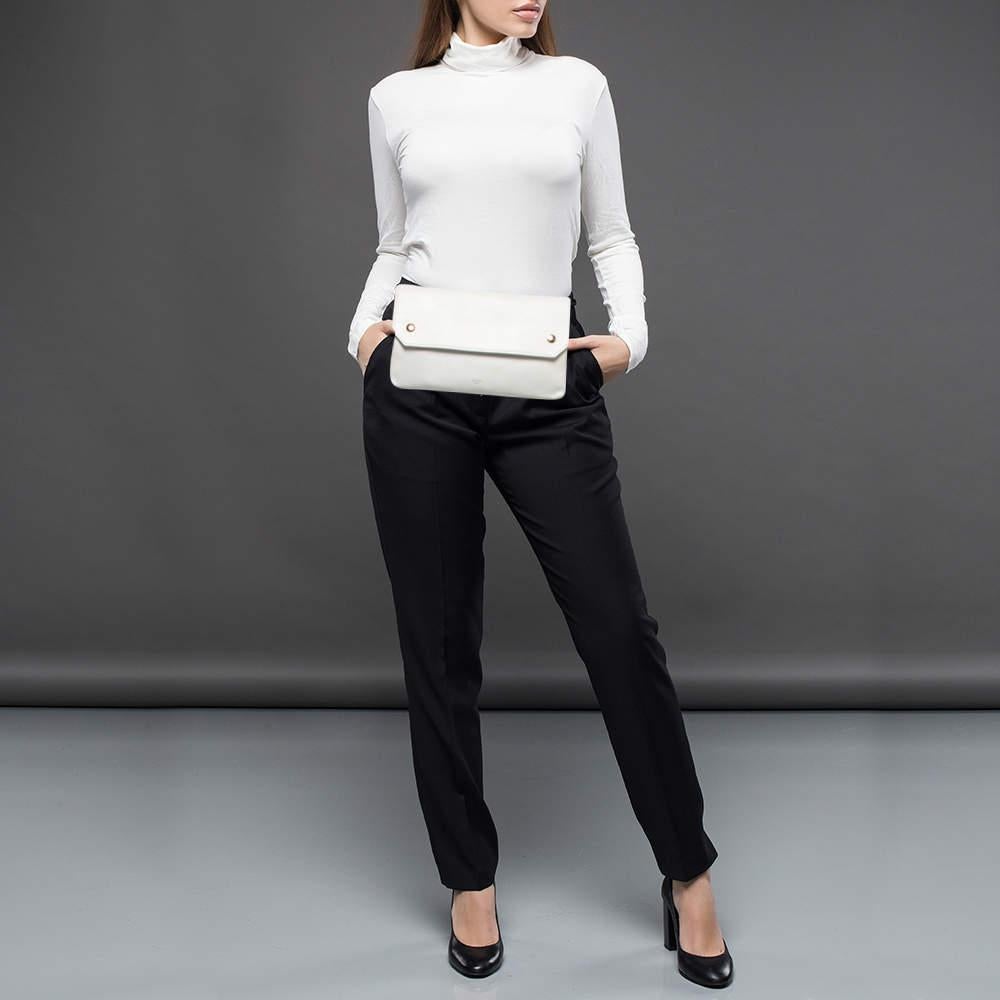 This Celine bum waist bag is crafted of luxuriously soft calfskin leather in white. In a sleek silhouette, it features an adjustable leather waist strap with a gold-tone buckle and a front flap with two gold-tone button snaps. The suede-lined