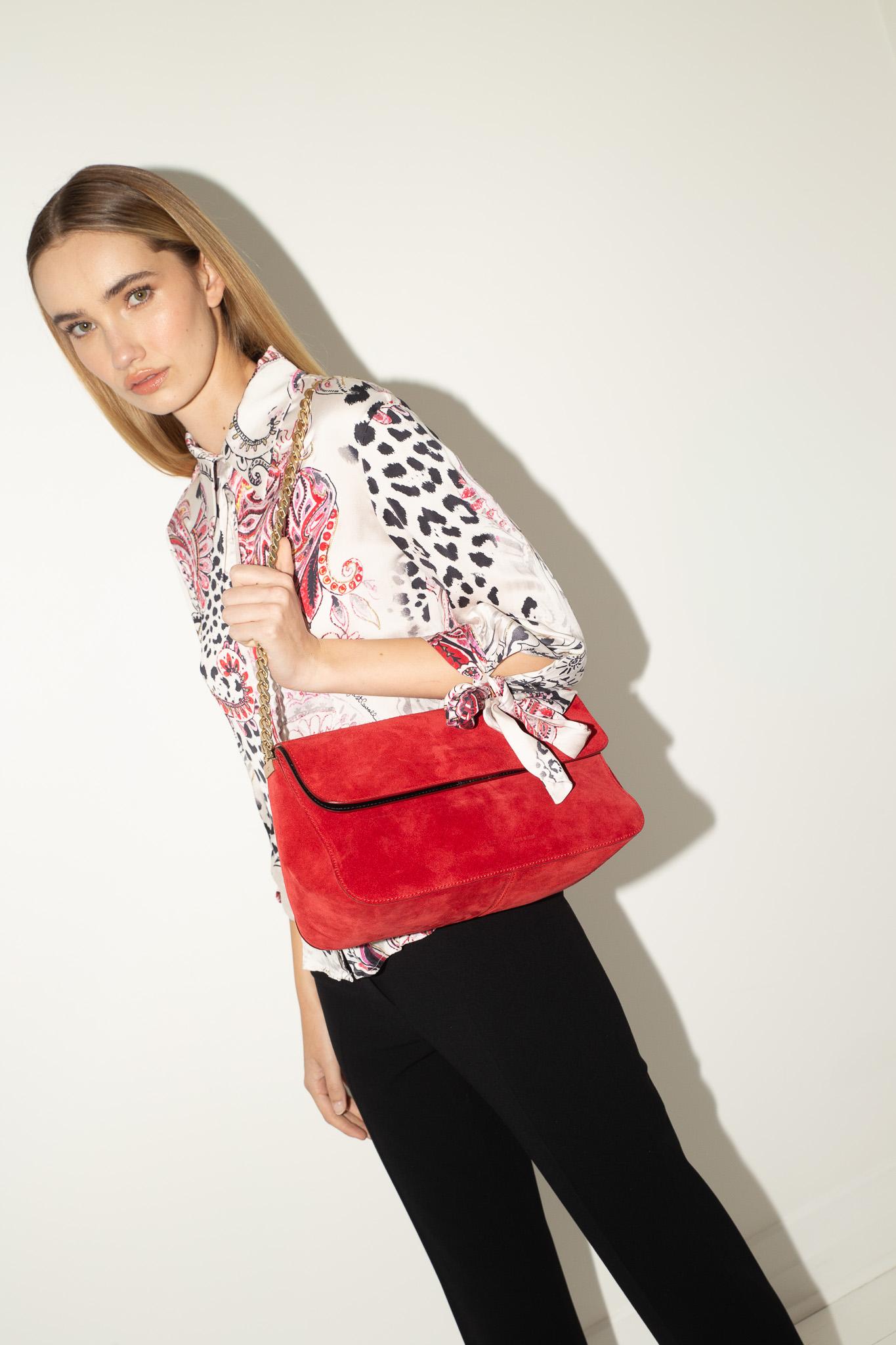 Designed under Phoebe Philo for Céline’s Resort 2012 collection, this red suede Gourmette bag is the epitome of understated luxury. Cut in a slouchy hobo silhouette, it features a bold gold-tone chain strap, branded Céline hardware, and a detachable