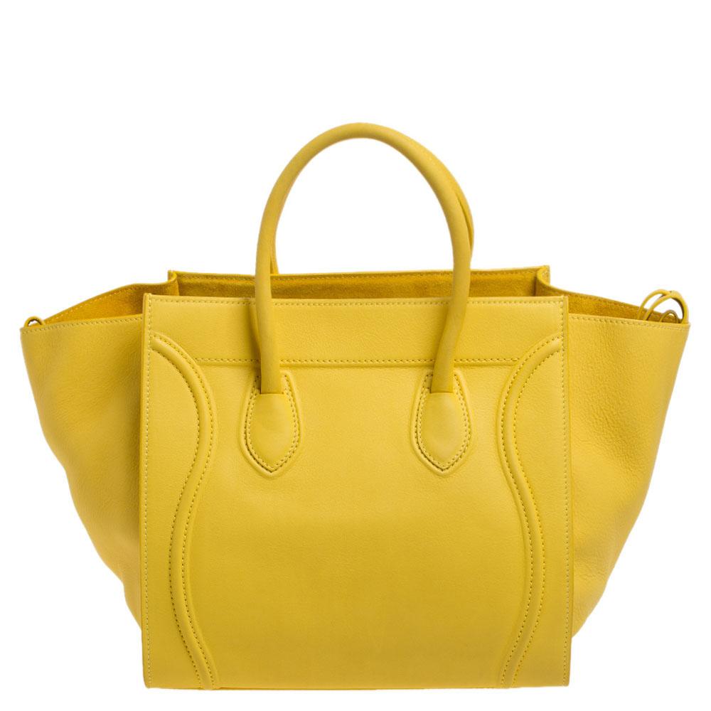 Celine released the Phantom as a newer version of its successful Luggage model. Unlike the Luggage toes, the Phantom has an open-top, wider wingspans, and a braided zipper pull. We have here the one in leather. It has two top handles, a yellow