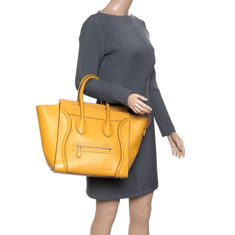 The iconic Mini Luggage tote from the house of Celine has had a cult following ever since its introduction. Featuring a chic trapeze shape, this bag is crafted in yellow leather with wings, two rolled top handles and is secured with a top zip