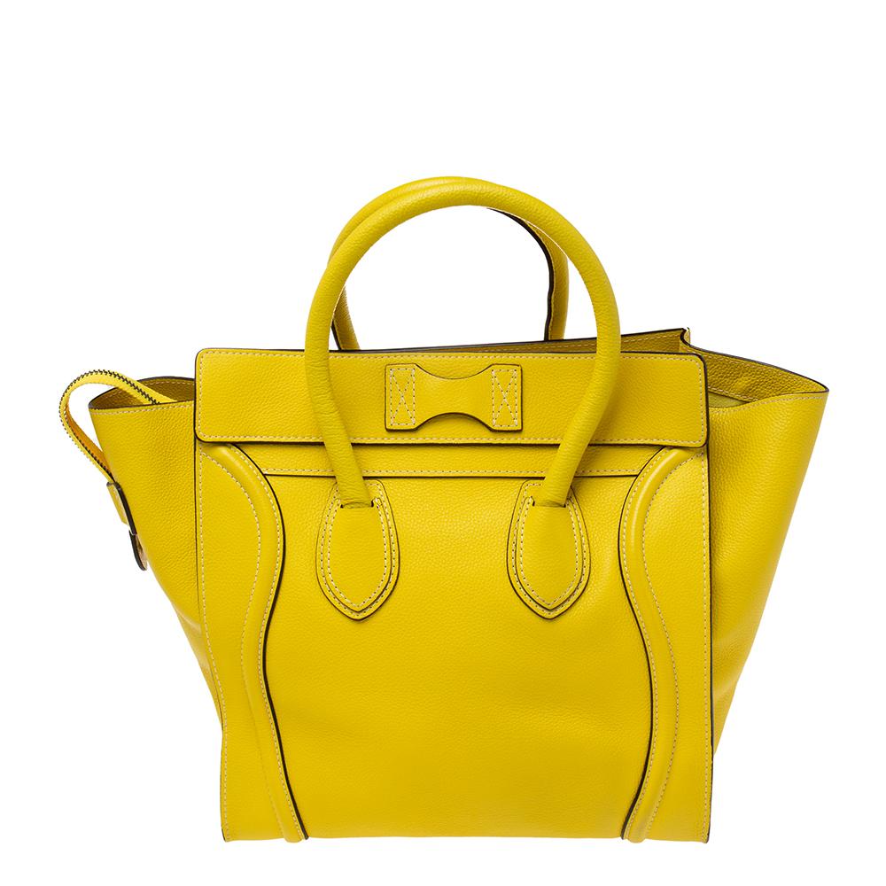 The mini Luggage tote from Celine is one of the most popular handbags in the world. This tote is crafted from leather and designed in a yellow shade. It comes with rolled top handles and a front zip pocket. The bag is equipped with a well-sized