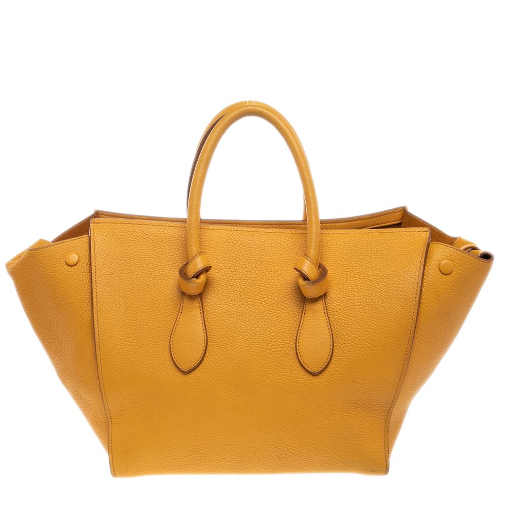 This Tie tote from Celine brings a wonderful mix of fashion and function. Expertly crafted from leather, it comes in a lovely shade of yellow with dual knot-detailed handles and metal studs to protect the base. Made in Italy, it has a spacious