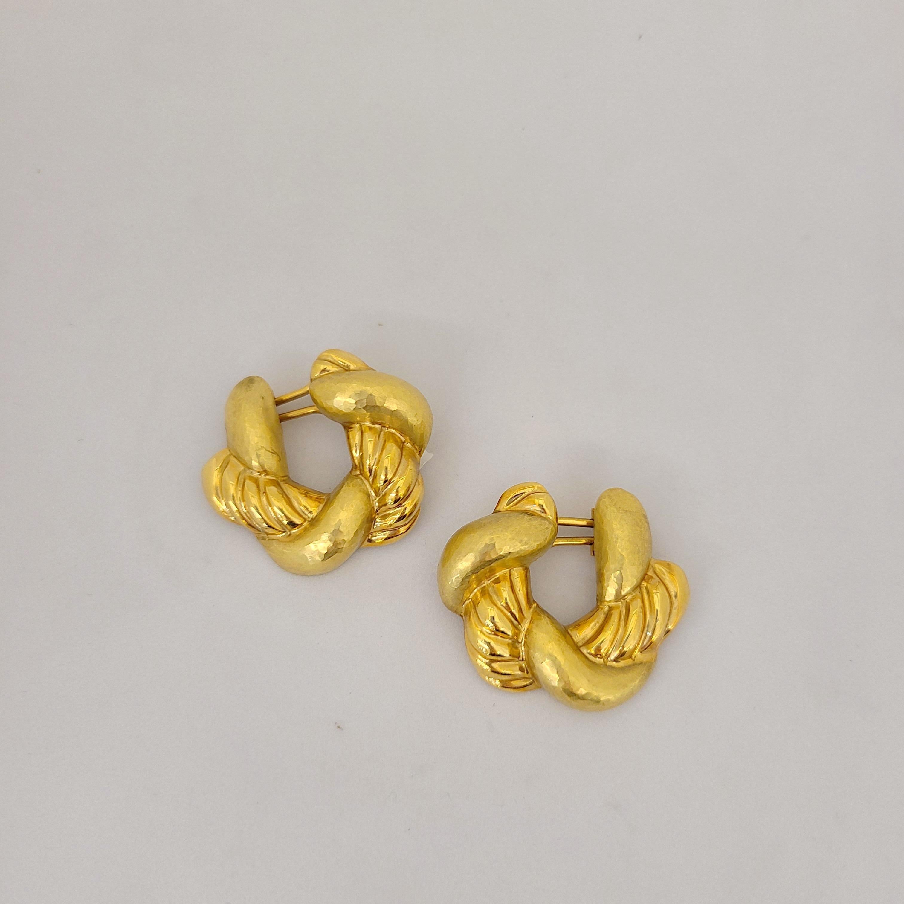 Cellini Jewelers NYC Classic and wearable 18 karat yellow gold hoop earrings are designed with a braid of alternating hammered and hi polished gold. The earrings are pierced with a french clip back. They measure 1-1/4