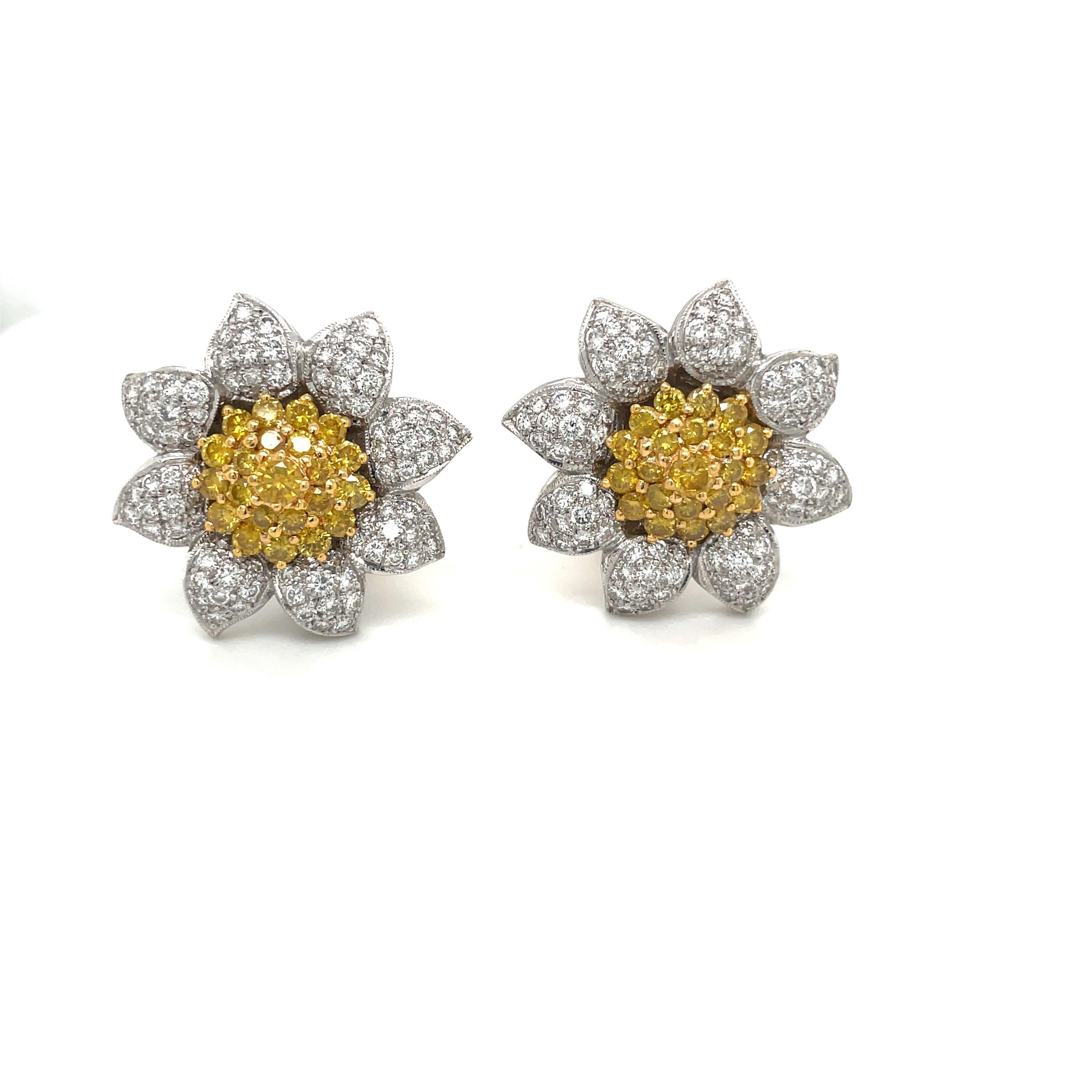 These charming flower earrings are comprised of 3.03 carats of brilliant white diamond pave set in the domed petals, surrounding an individually-set cluster of round fancy yellow diamonds, weighing a total of 2.32Ct.
The earrings have a flexible