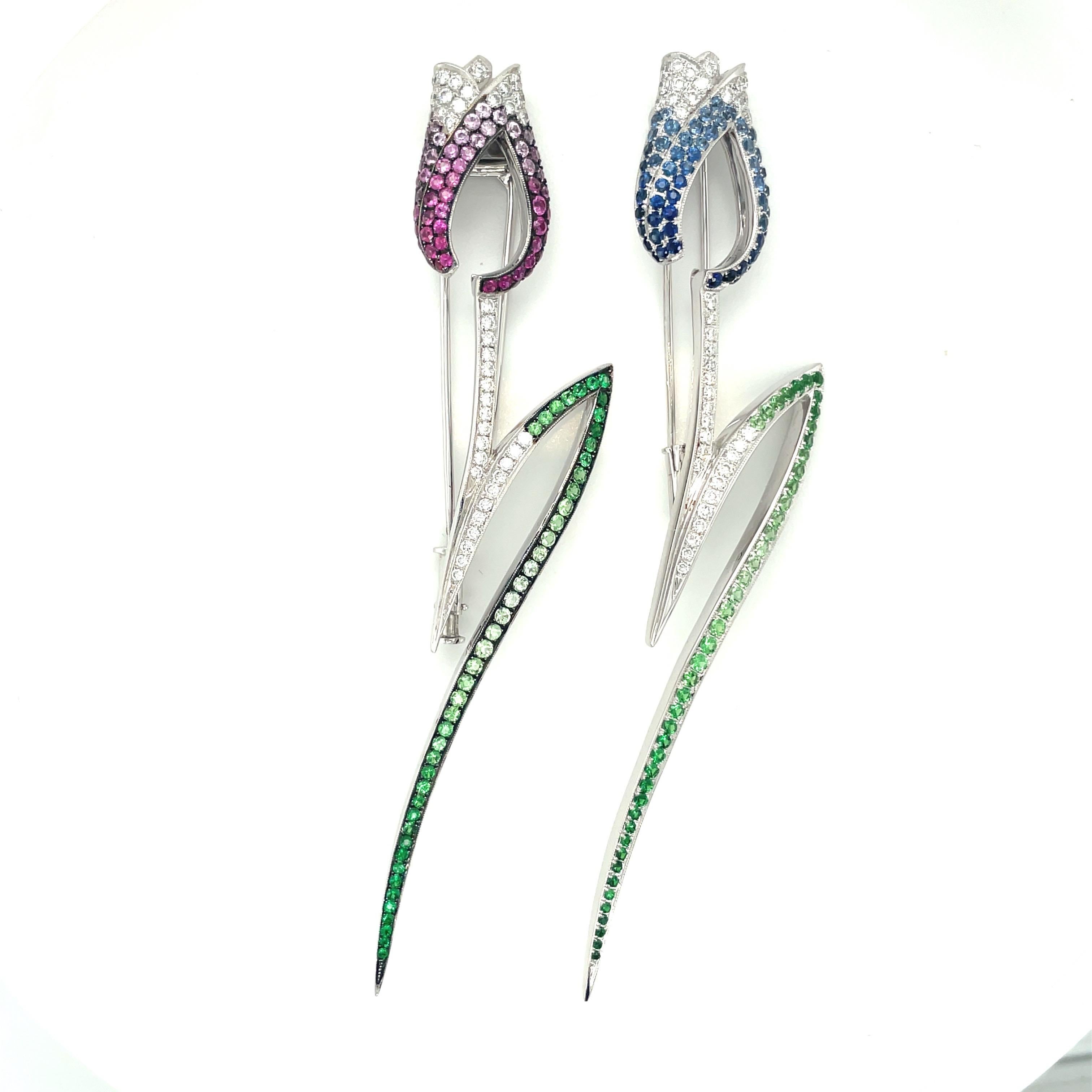 A beautifully designed 18 karat white gold tulip brooch. The flower is set with with shades of dark, transitioning to light blue sapphires . Shades of green tsavorites are set as the leaf, with round brilliant diamonds accenting  this graceful tulip