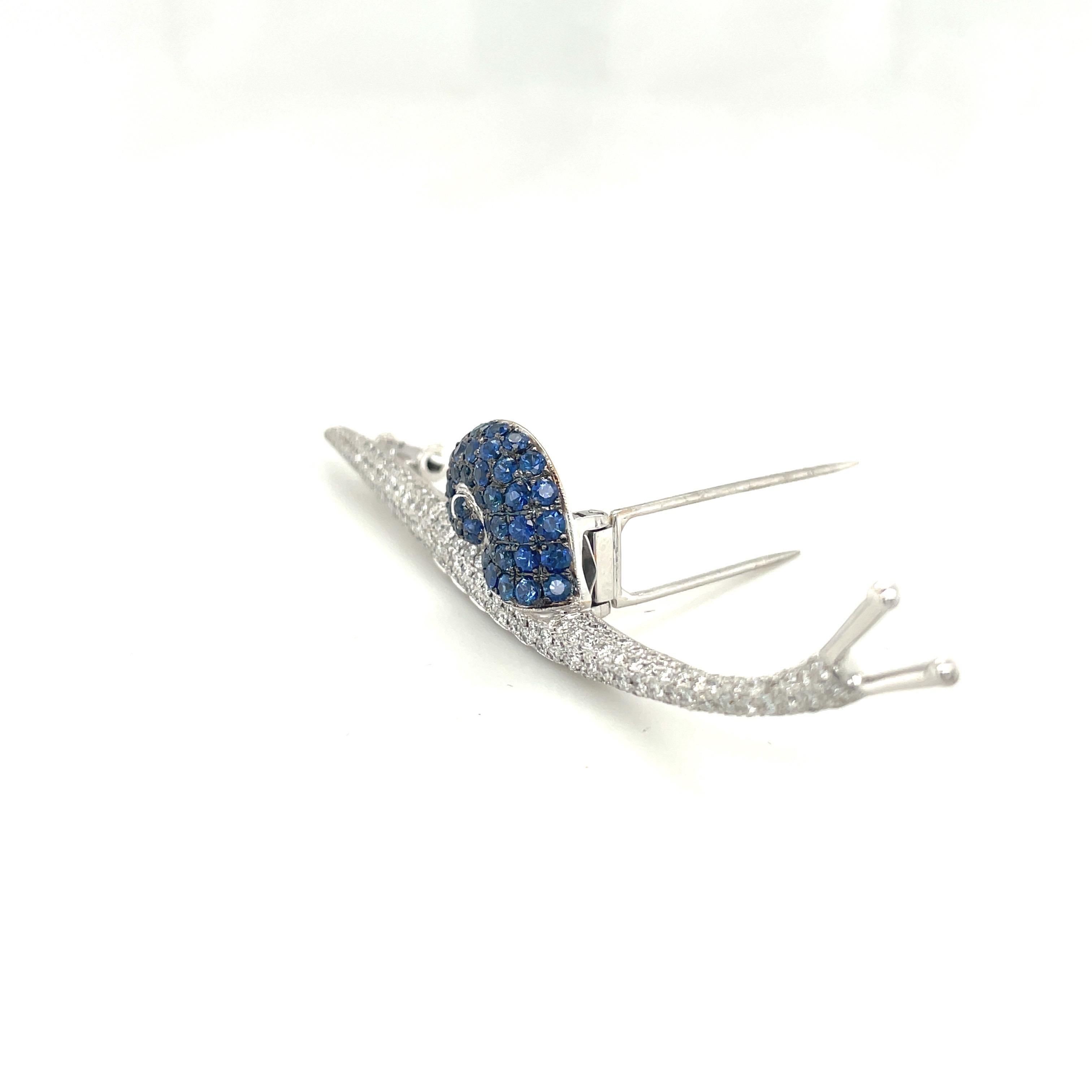 Cellini Jewelers NYC, Lovely snail brooch ,artistically designed in 18 karat white gold. The body is set with 1.80 carats of round brilliant diamonds, and the shell is set with 2.50 carats of round blue sapphires. The snail is 3.25