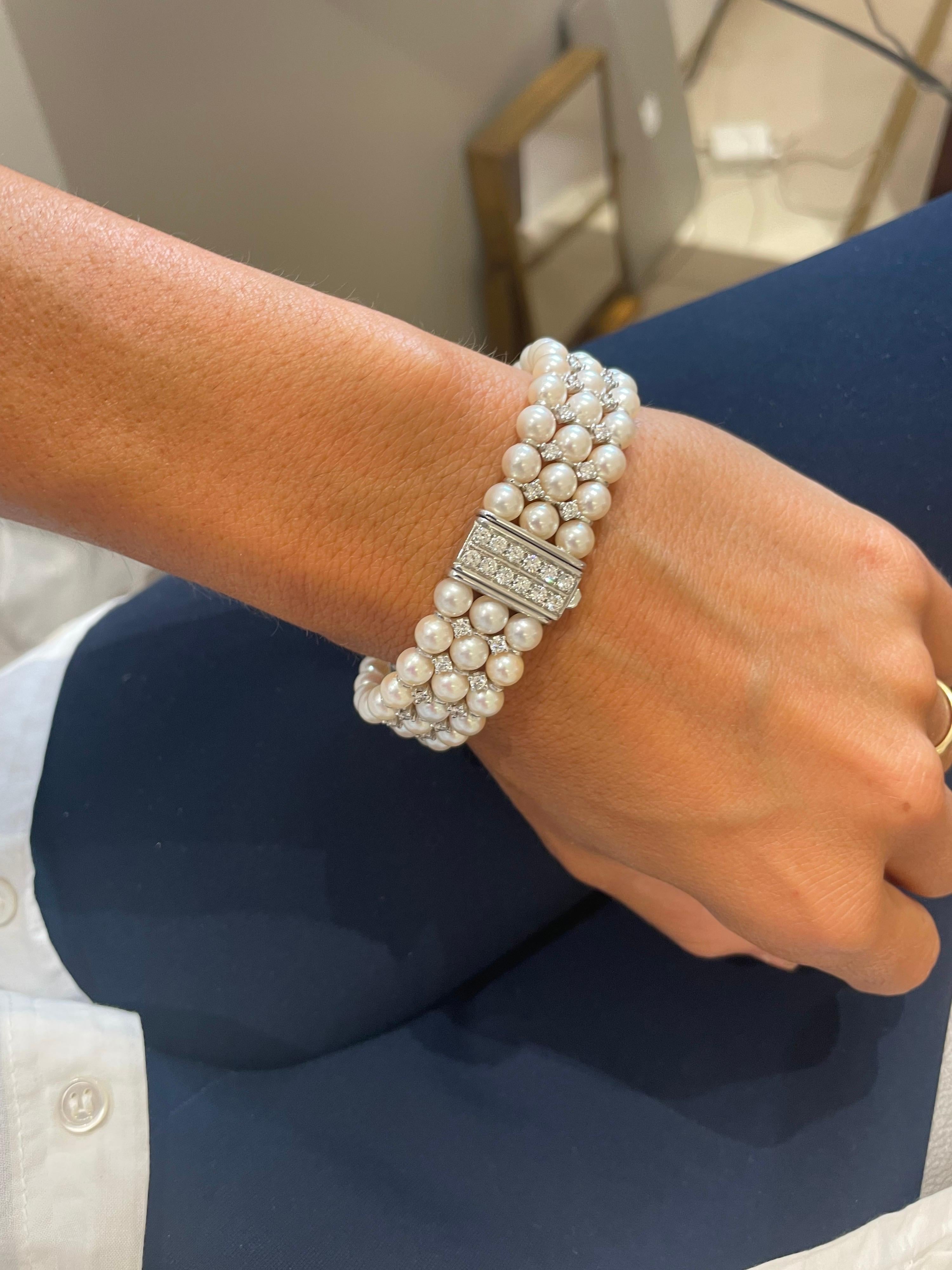 This gorgeous 18 karat white gold bracelet is designed with 3 rows of 5mm cultured pearls. The pearls alternate with round brilliant diamonds that have been prong set. The clasp is set with 12 round brilliant diamonds leading to continuous sparkle